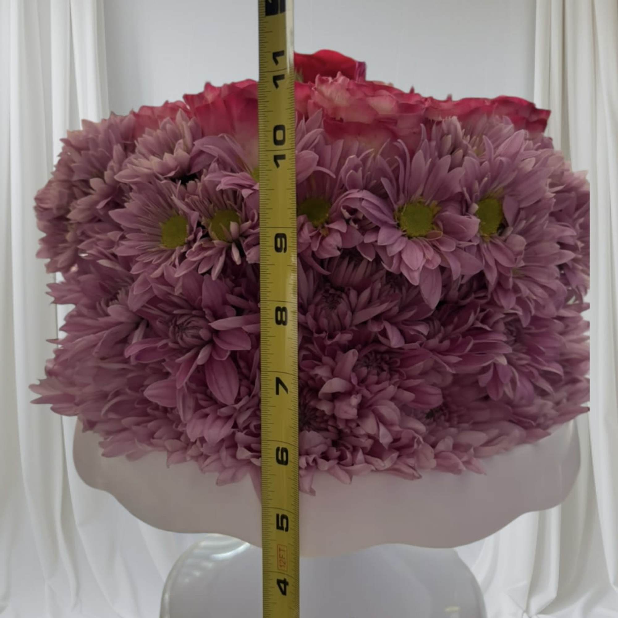 Pink chrysanthemum bouquet in a white vase with a measuring tape in front