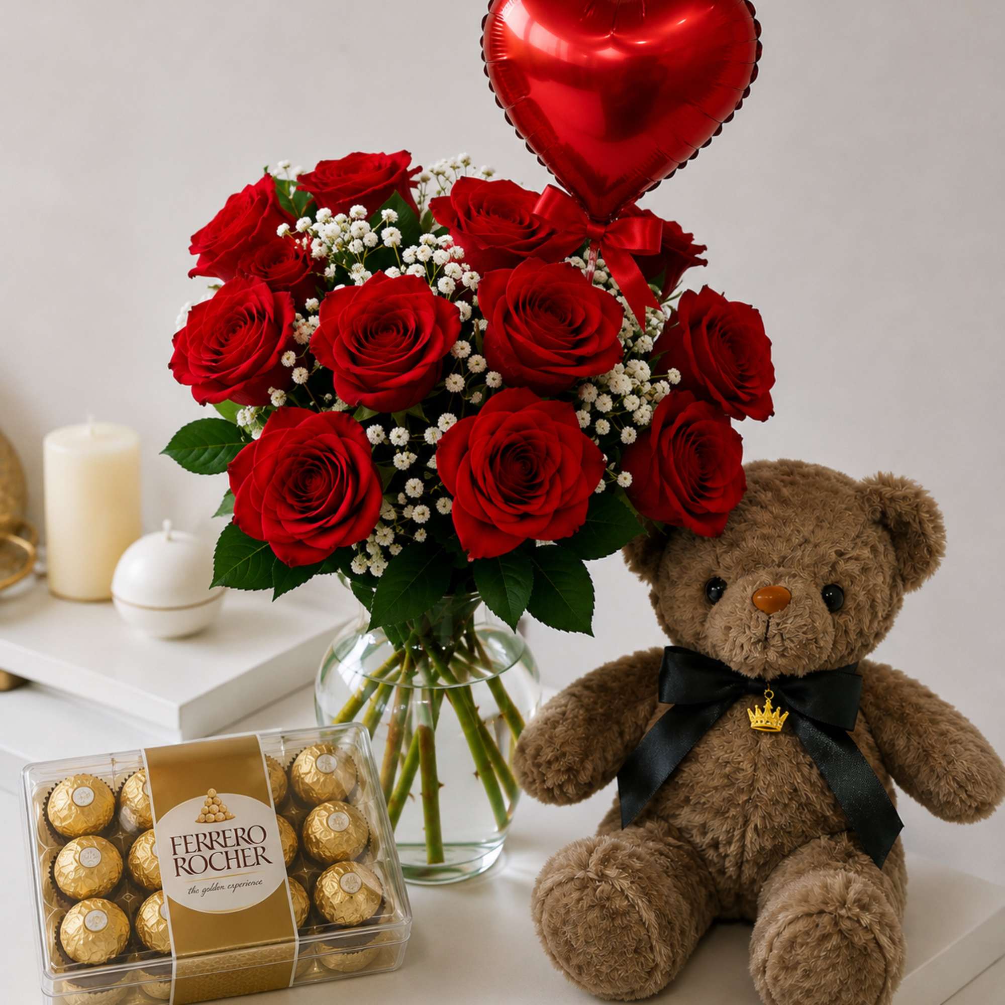 Red roses in a vase with a heart balloon, teddy bear, and chocolates