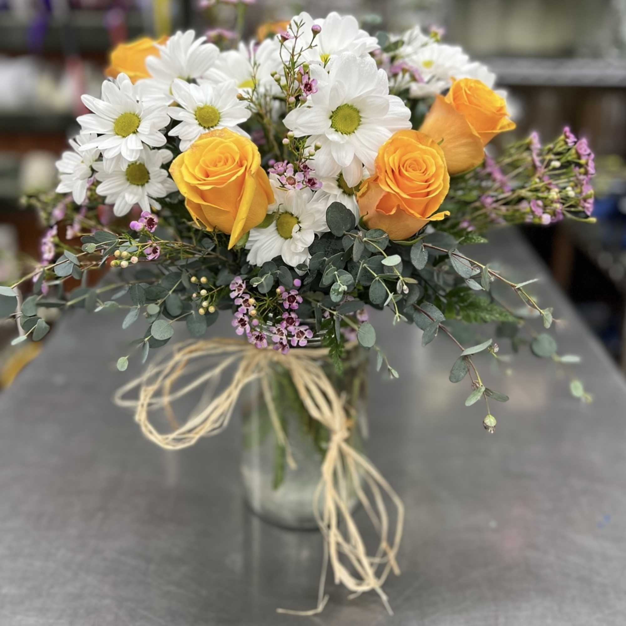 Bouquet of orange roses and white daisies in a glass vase
