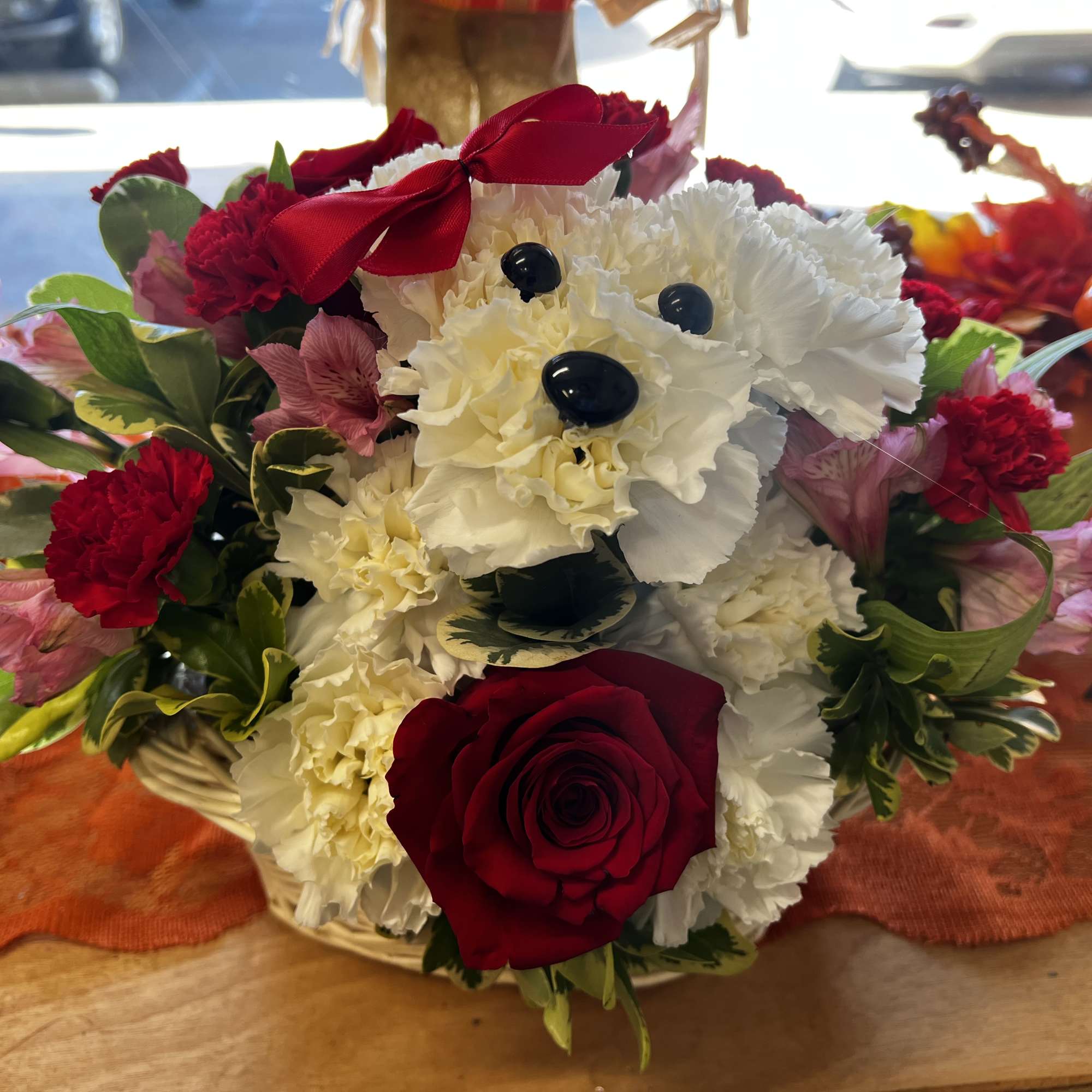 A cute Puppy with White carnations and a red rose.