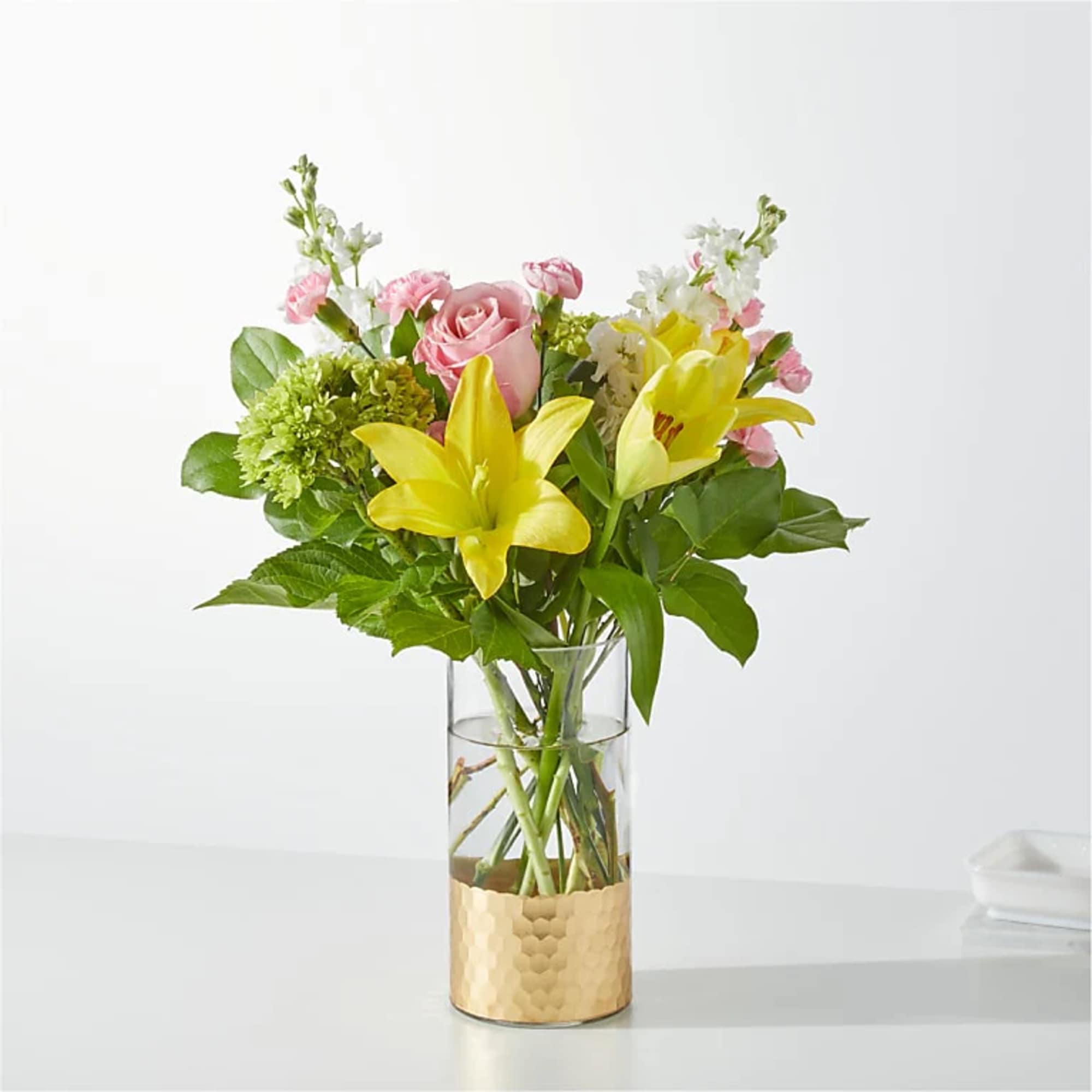 Pink roses and yellow lilies in a clear glass vase