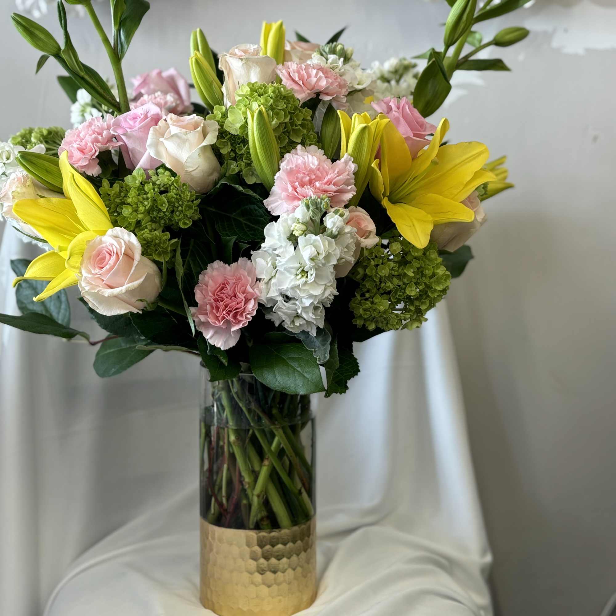Bouquet of pink and white flowers with yellow lilies in a glass vase