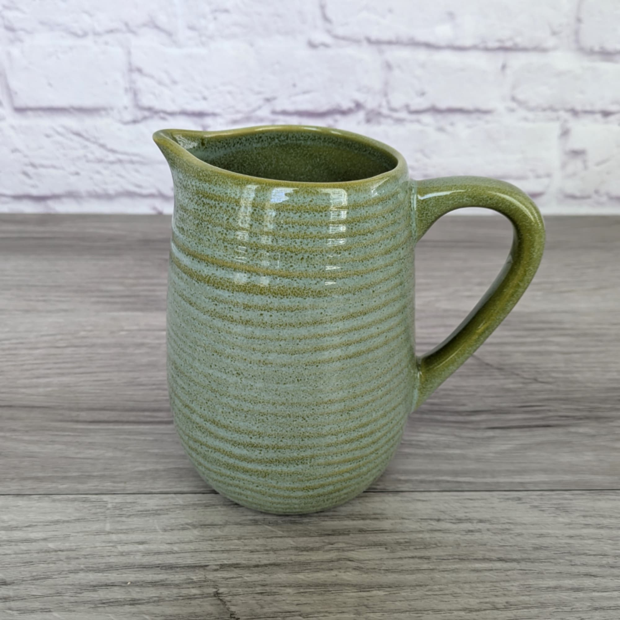 Green ceramic pitcher on a wooden surface