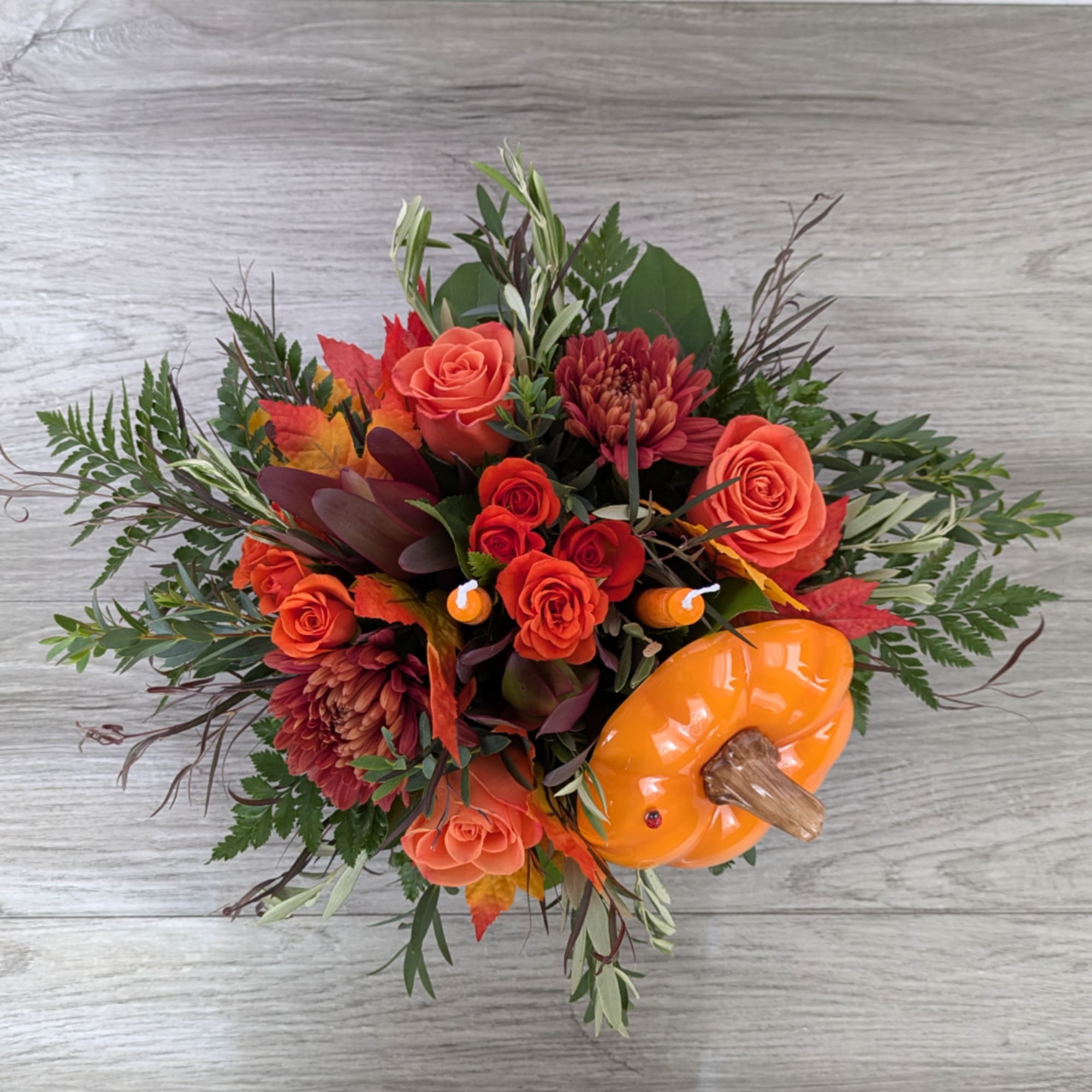 Orange roses and burgundy mums with a pumpkin accent