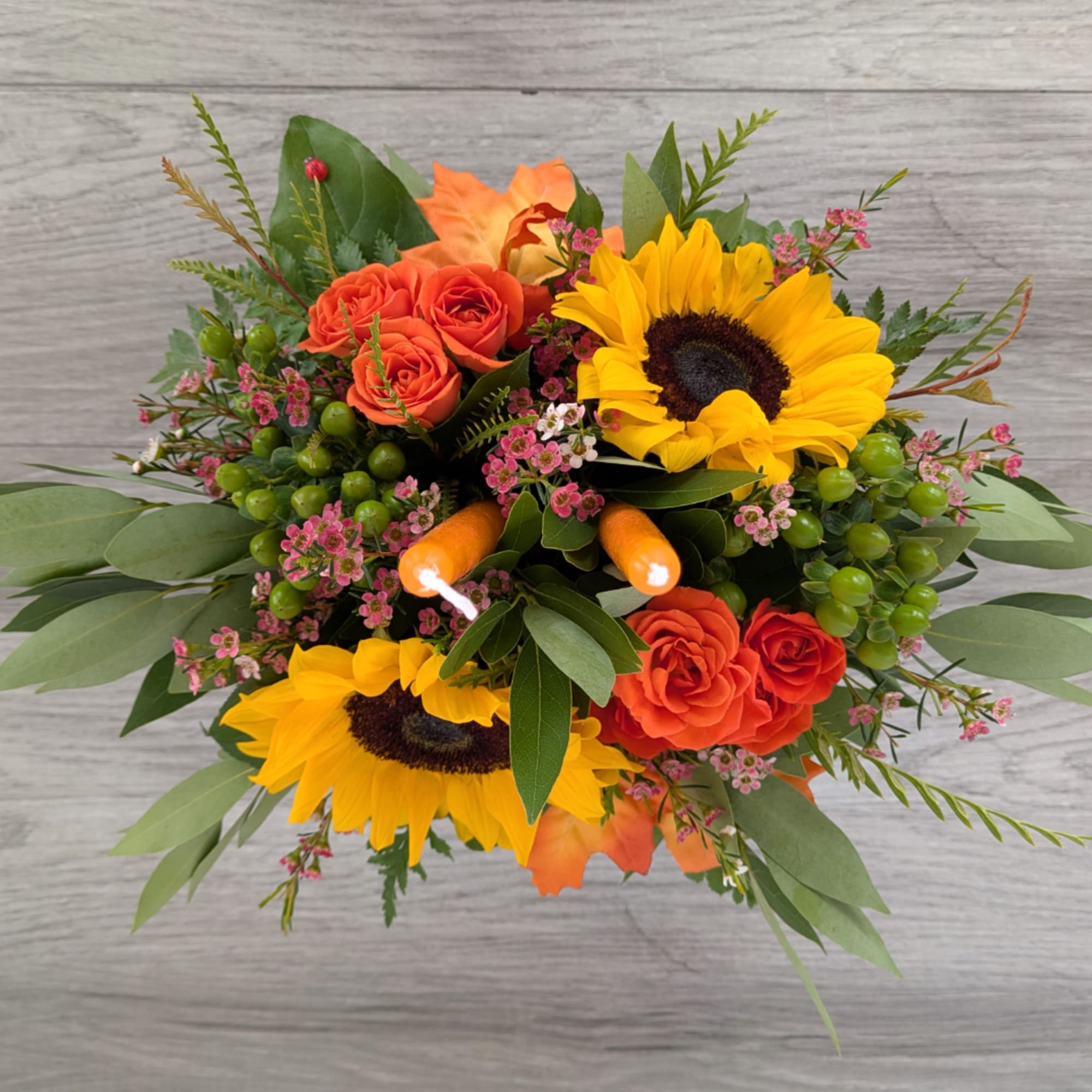 Sunflowers and orange roses in a low bouquet with greenery