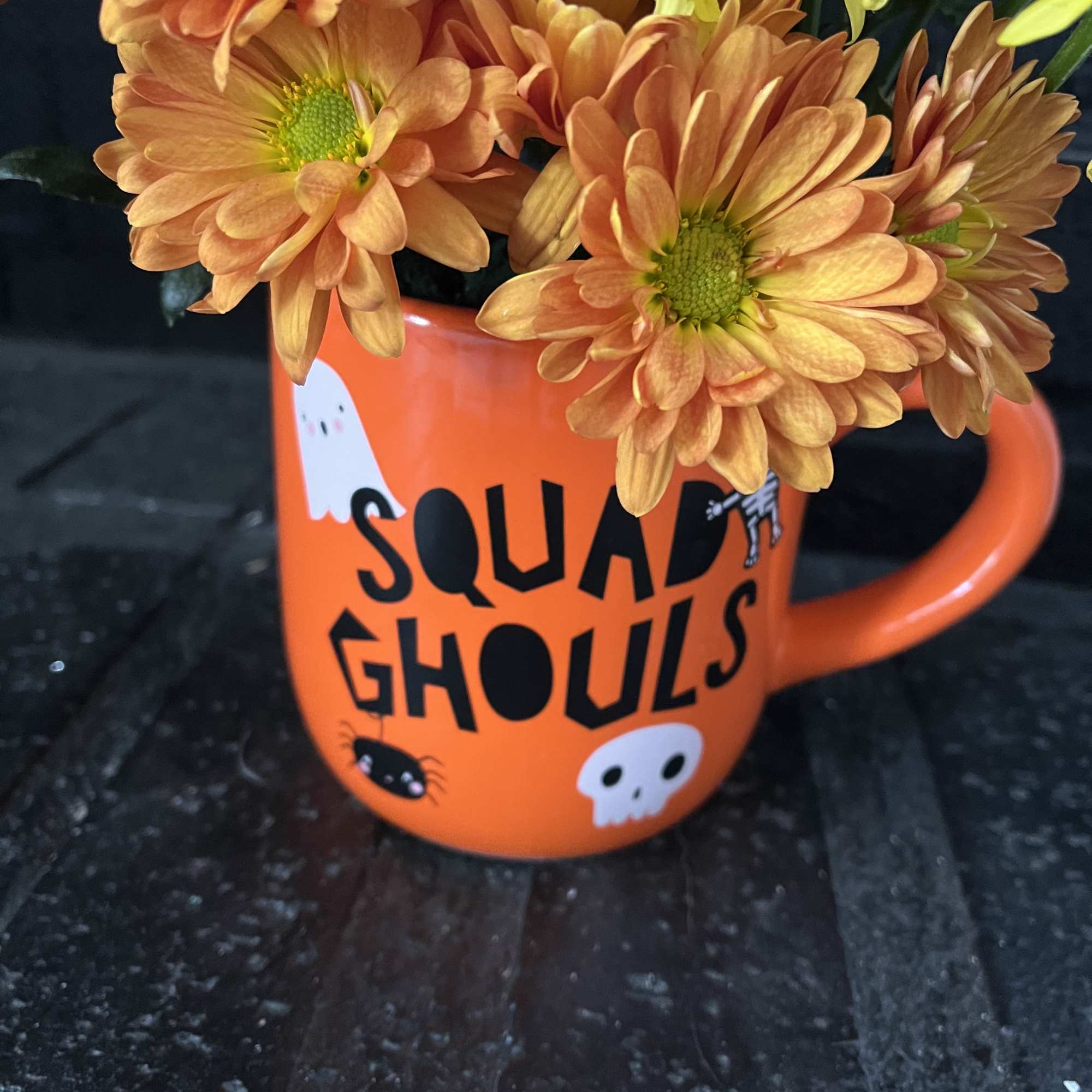 Orange and yellow daisies in a Halloween mug with ghost graphics