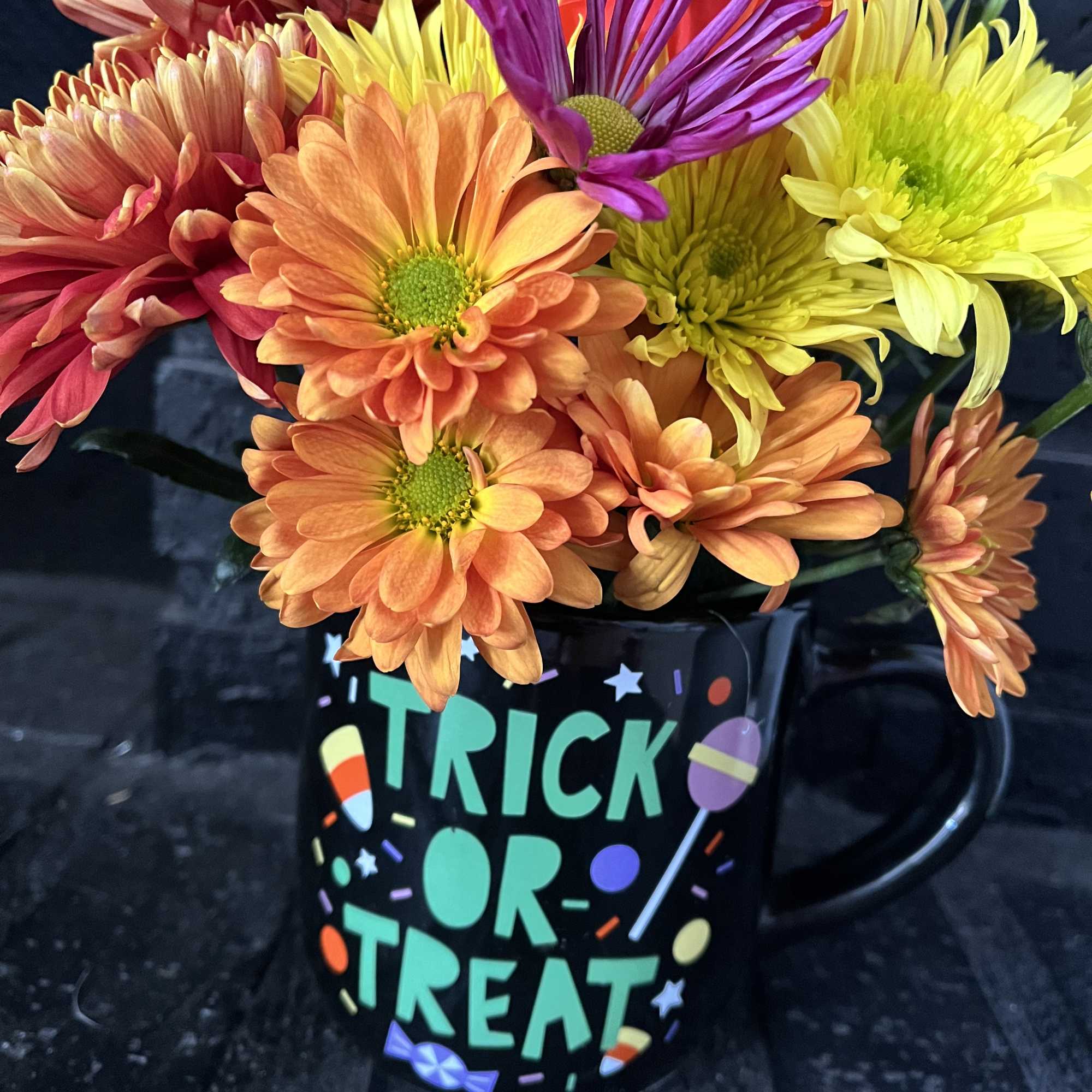Bouquet of colorful daisies in a Halloween mug