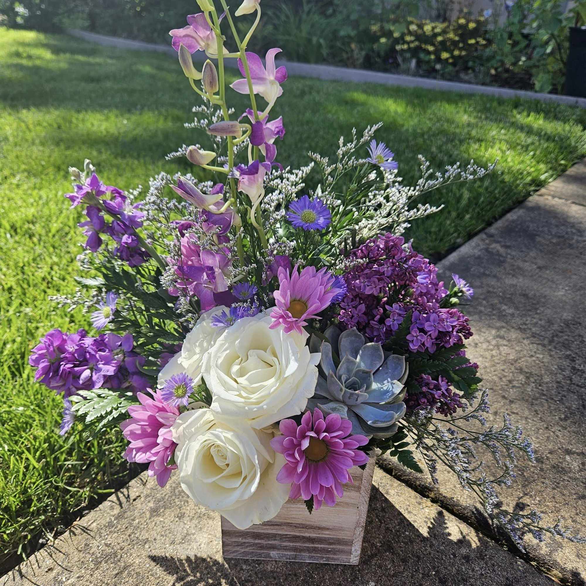 Purple and white floral arrangement in a wooden box with a succulent