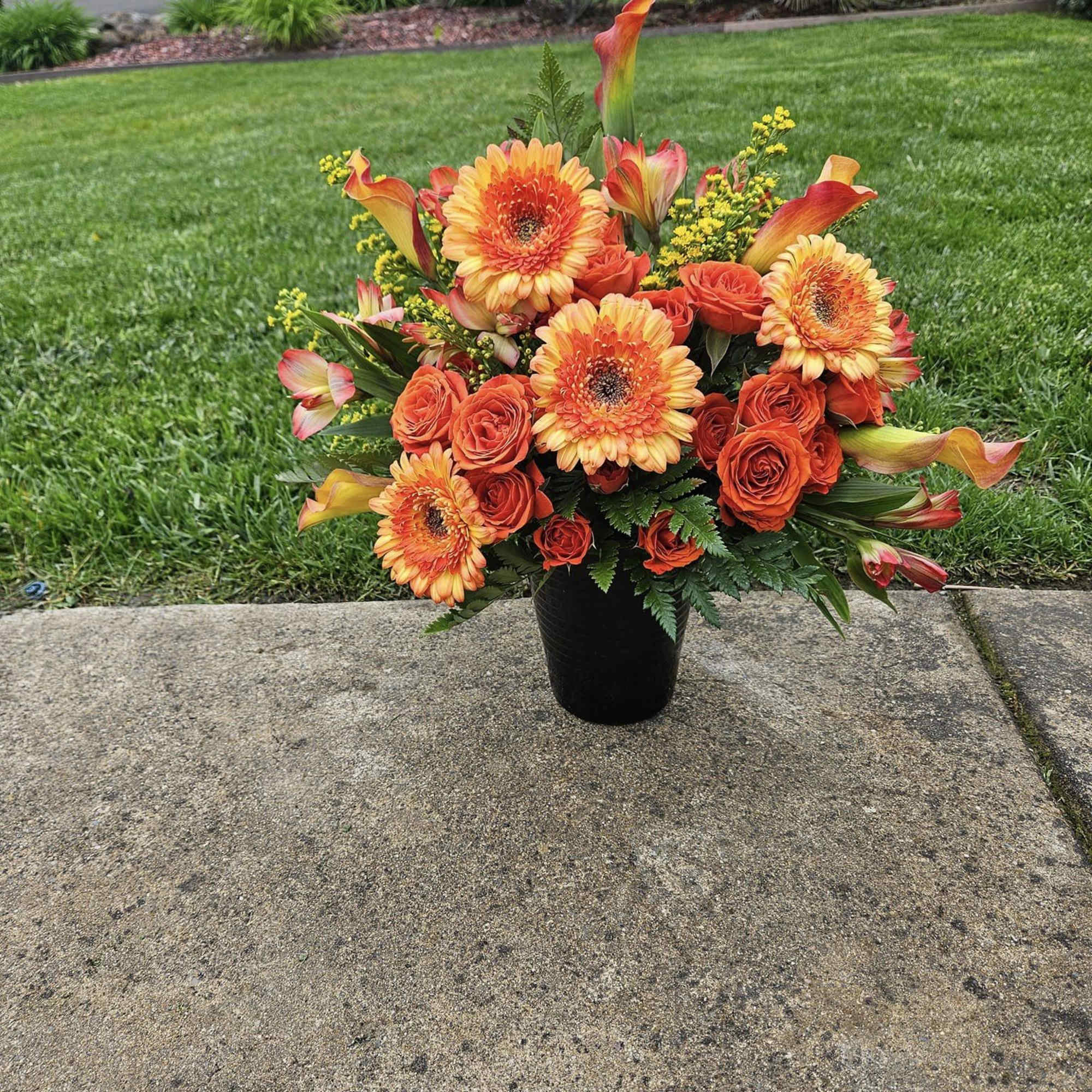 Orange and yellow floral arrangement in a black vase