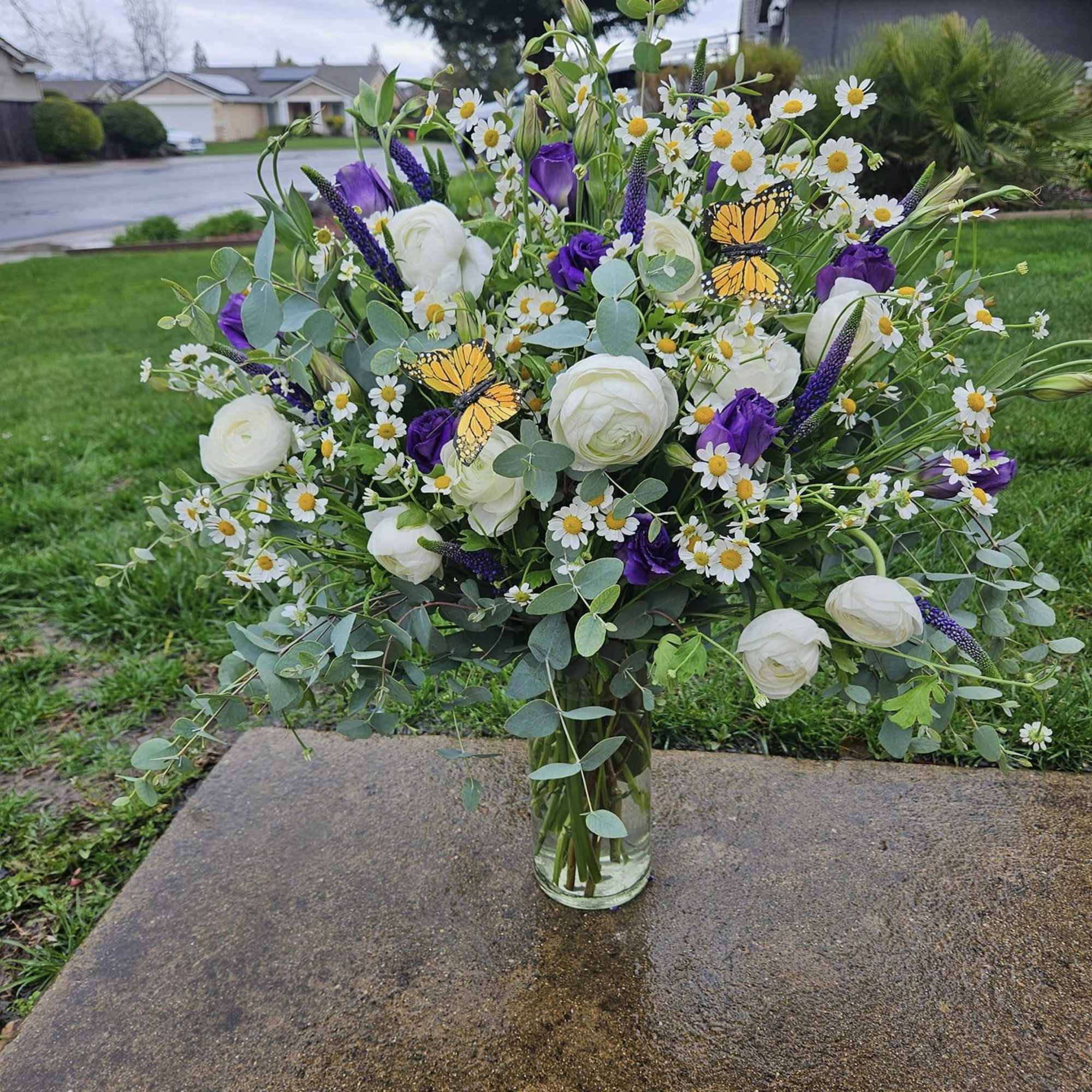 Large bouquet of white and purple flowers in a glass vase