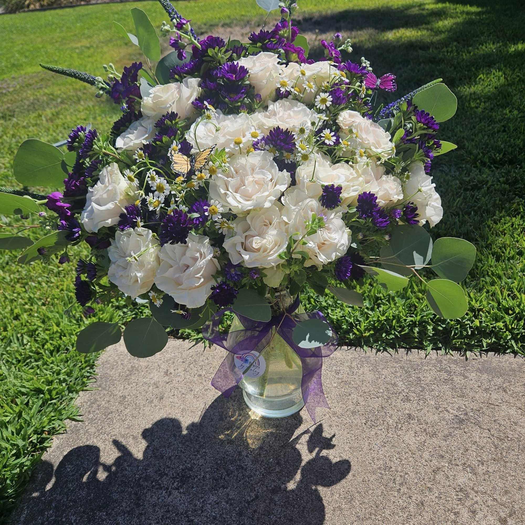Bouquet of white roses and purple flowers in a glass vase