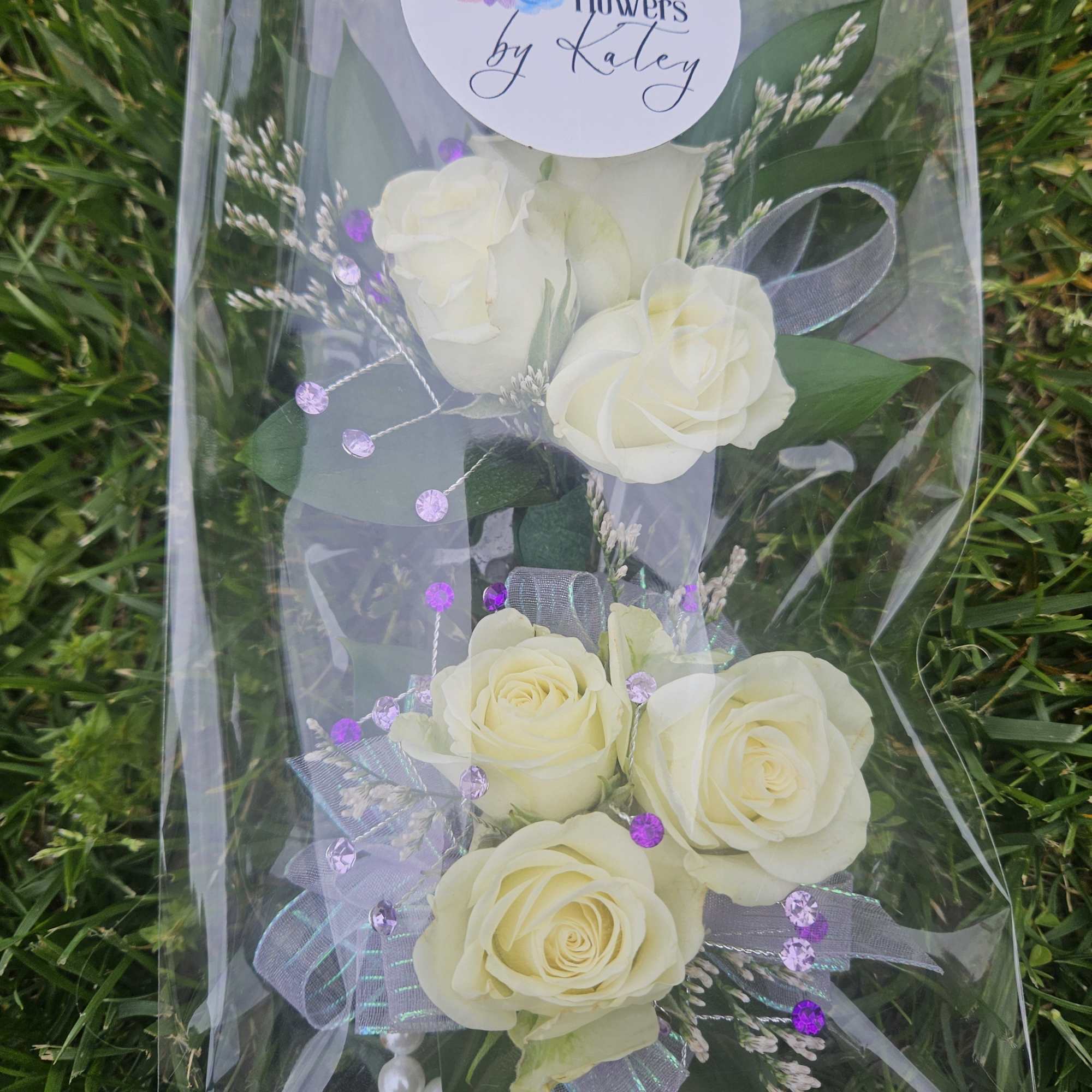 Wrapped bouquet of white roses with purple accents