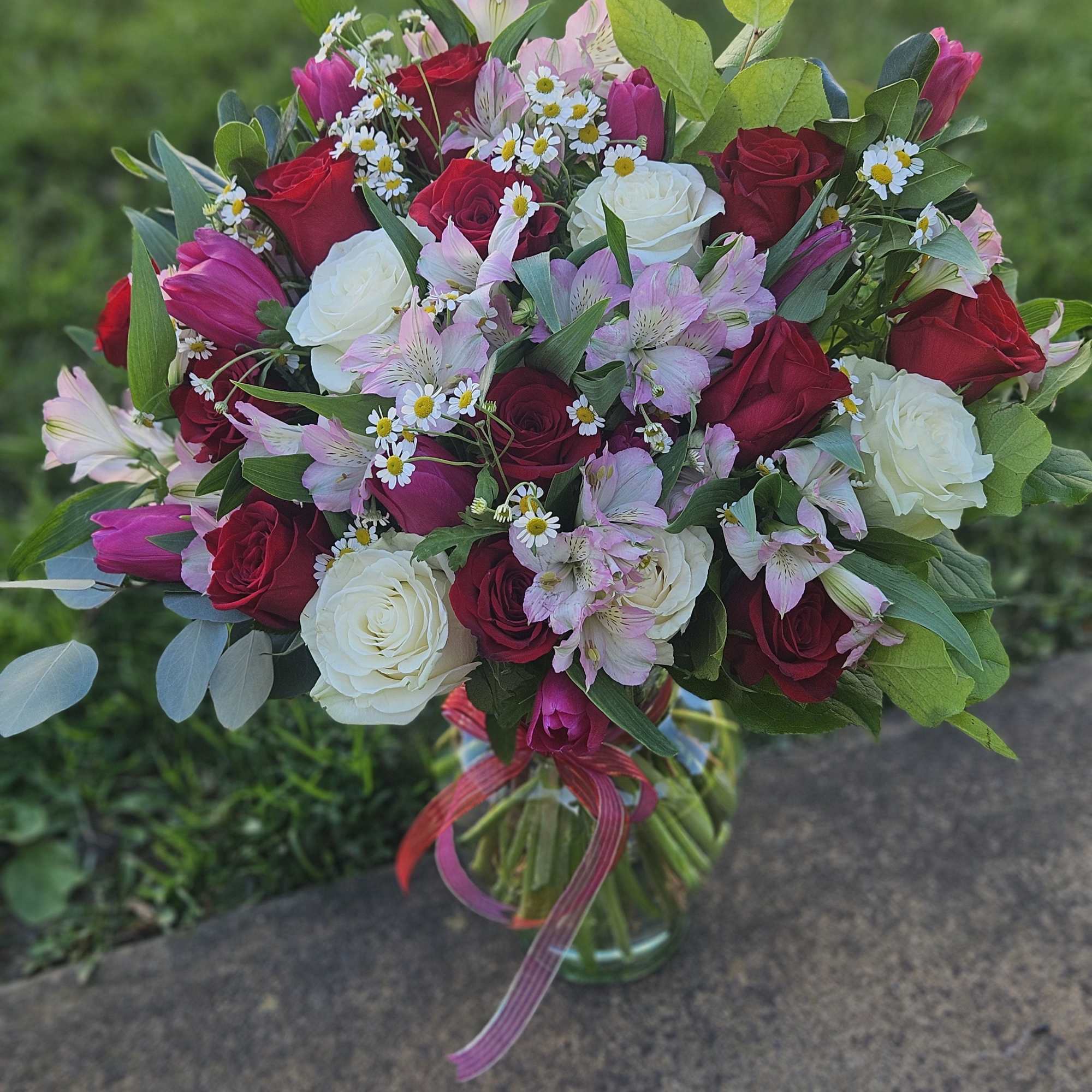 Bouquet of red and white roses with pink alstroemeria and daisies in a glass vase