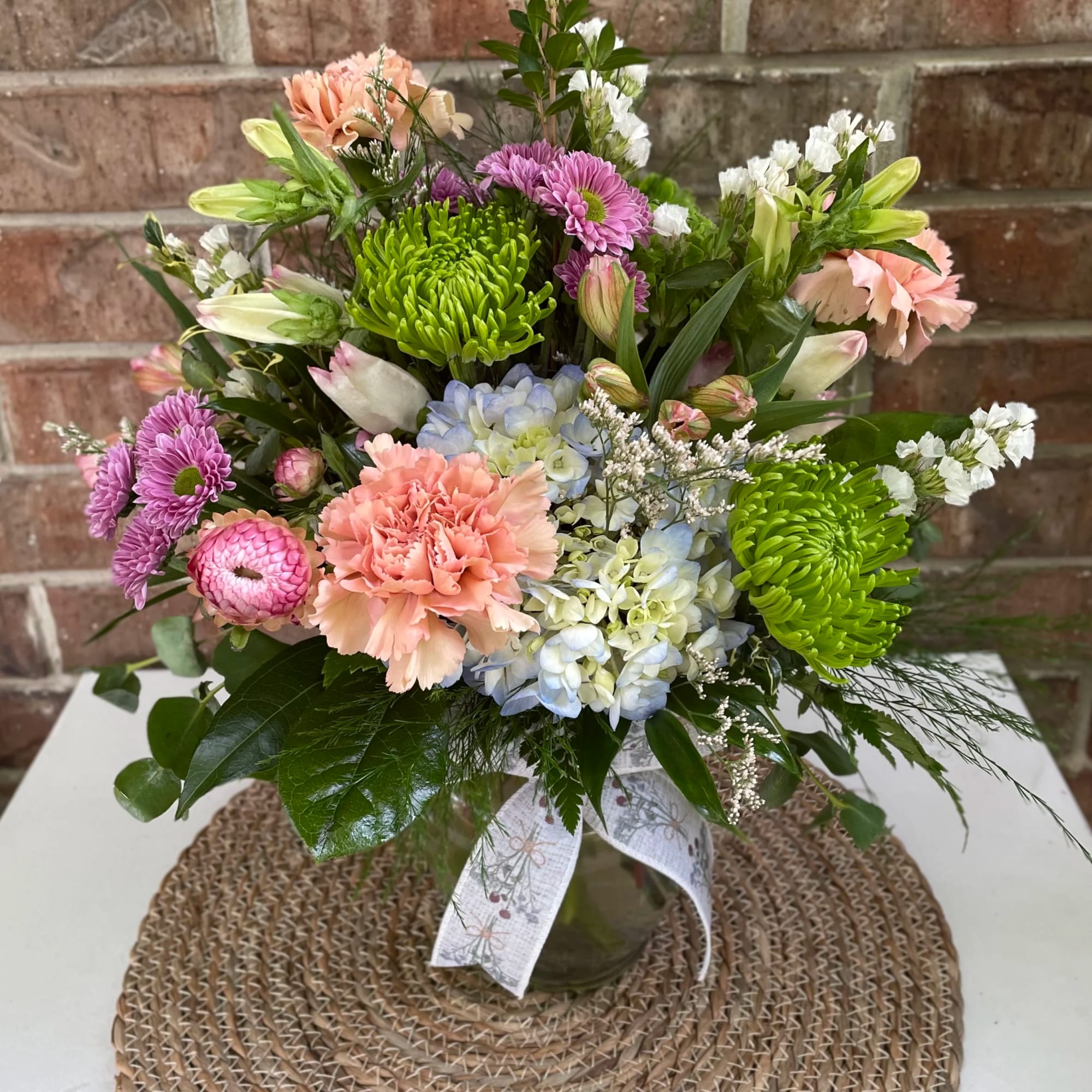 Mixed bouquet in a glass vase with pink, purple, blue, and green blooms