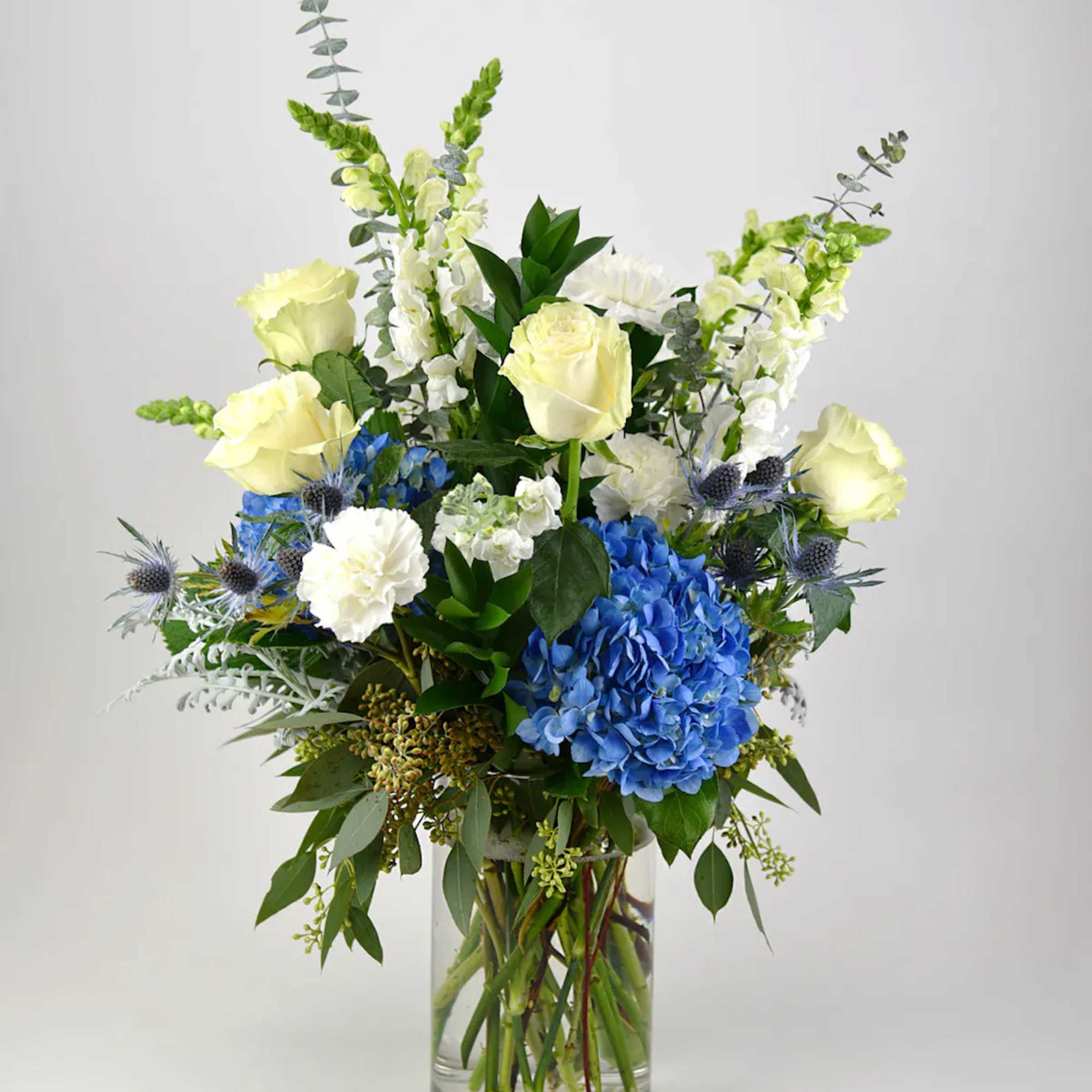 This heavenly arrangement of white flowers with blue accent blooms sends a