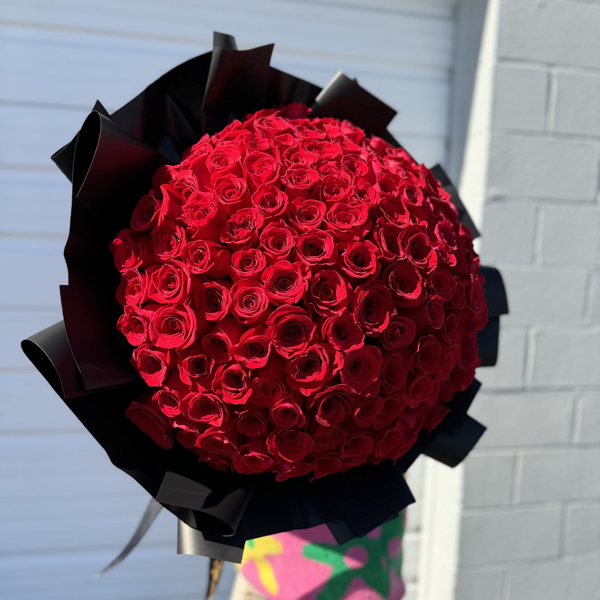 Large bouquet of red roses wrapped in black paper
