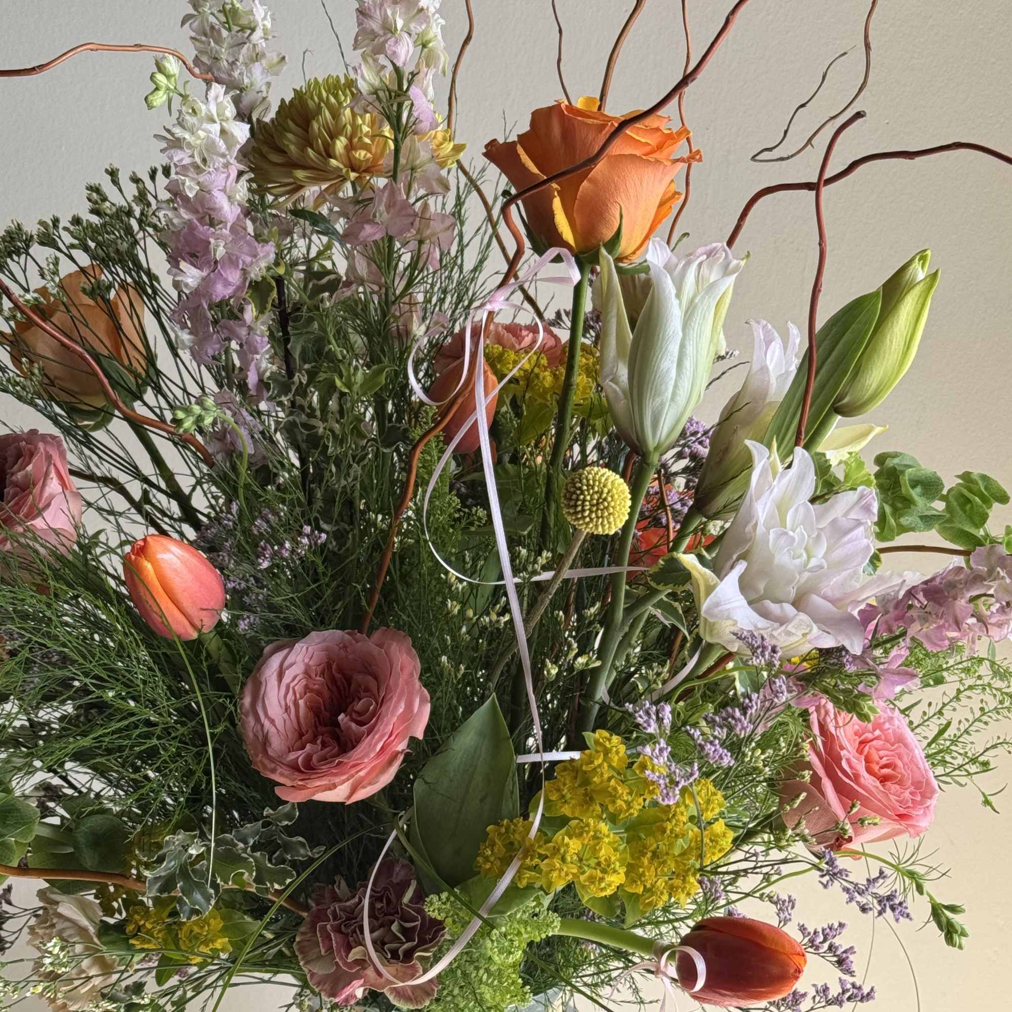 Tall mixed bouquet with roses, tulips, and white blooms in a glass vase