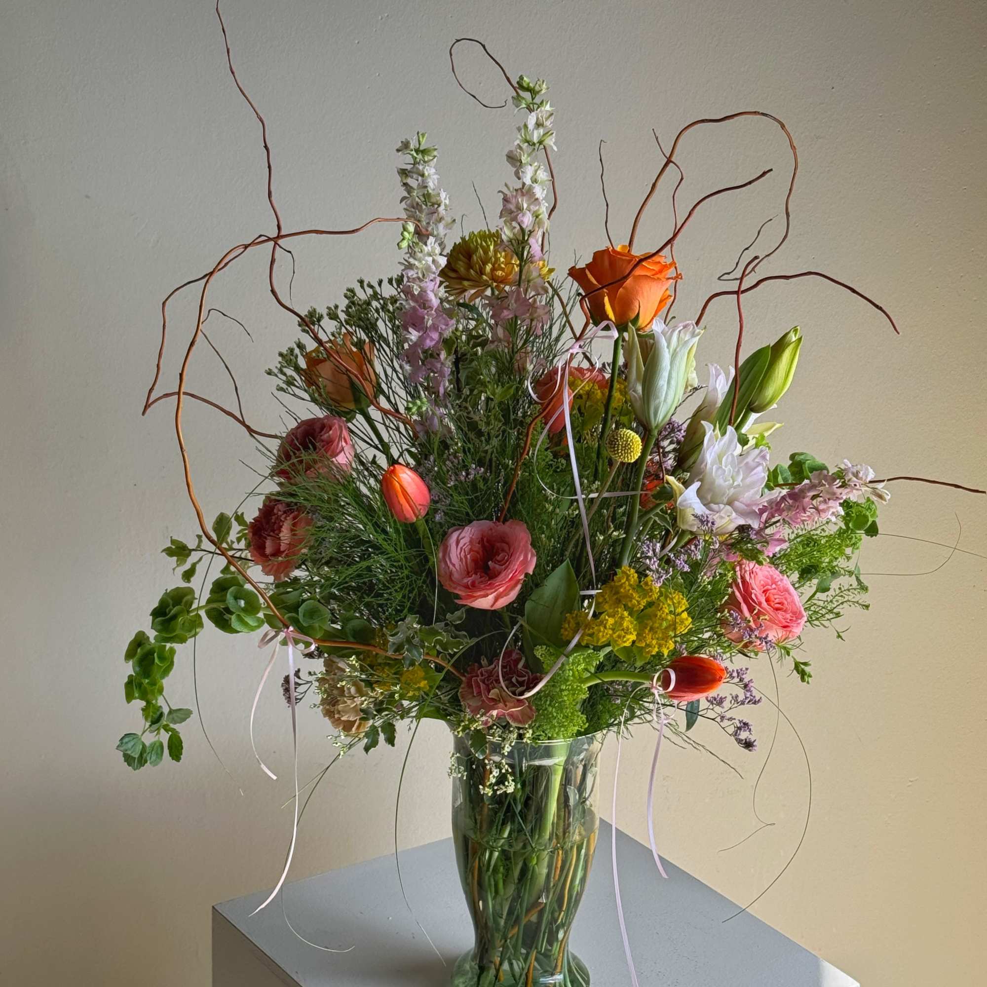 Tall mixed bouquet in a glass vase with orange, pink, and white blooms