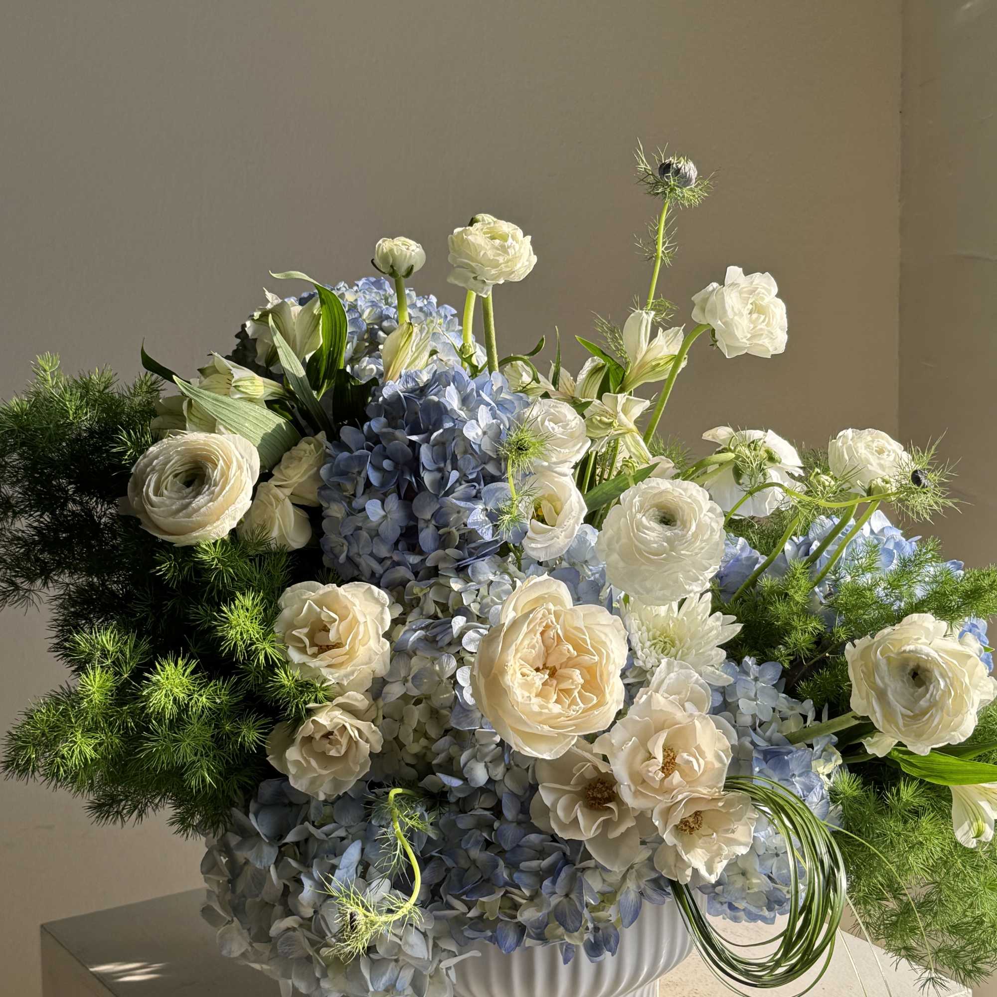 Blue hydrangea and white flower arrangement in a white vase