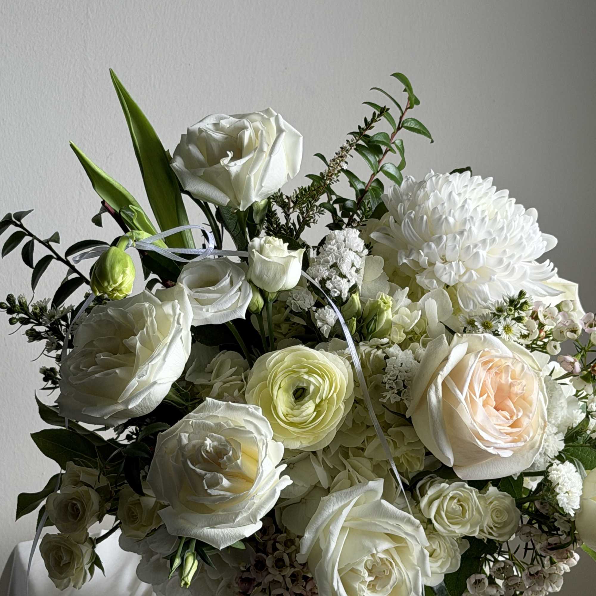 White rose and chrysanthemum bouquet in a black vase