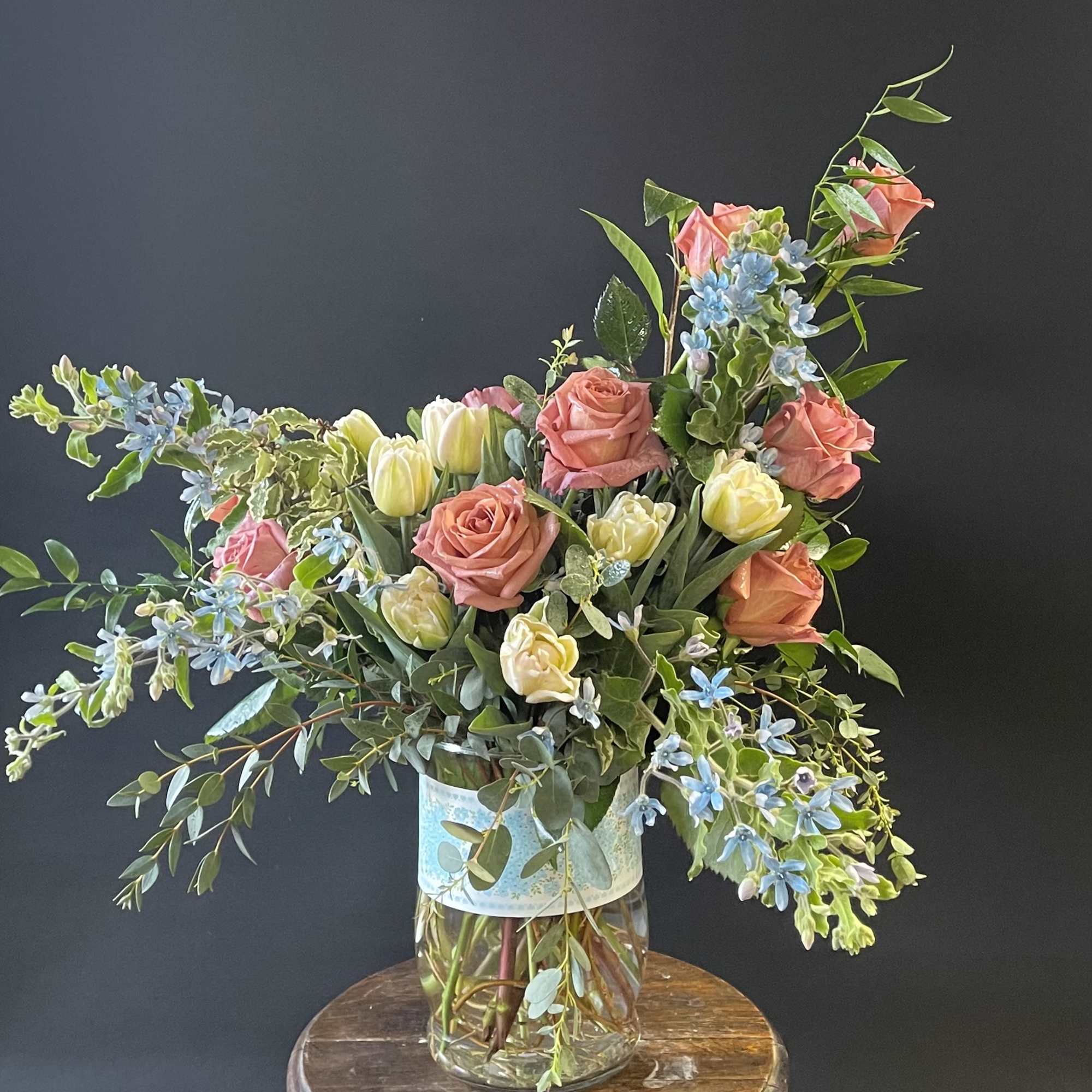 Mixed bouquet of pink roses and pale tulips in a glass vase