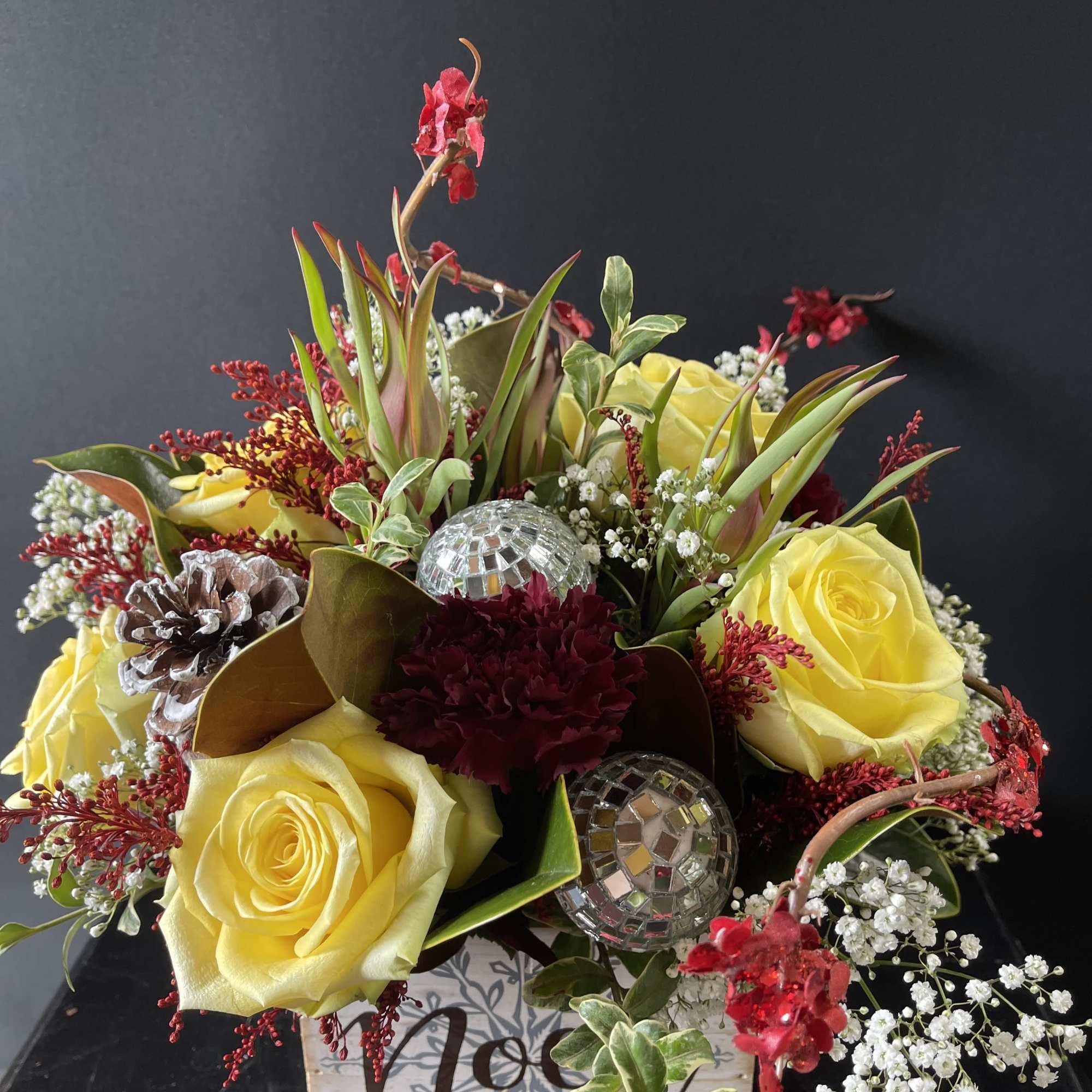 Yellow roses and burgundy flowers arranged in a decorative box with mirrored ornaments.