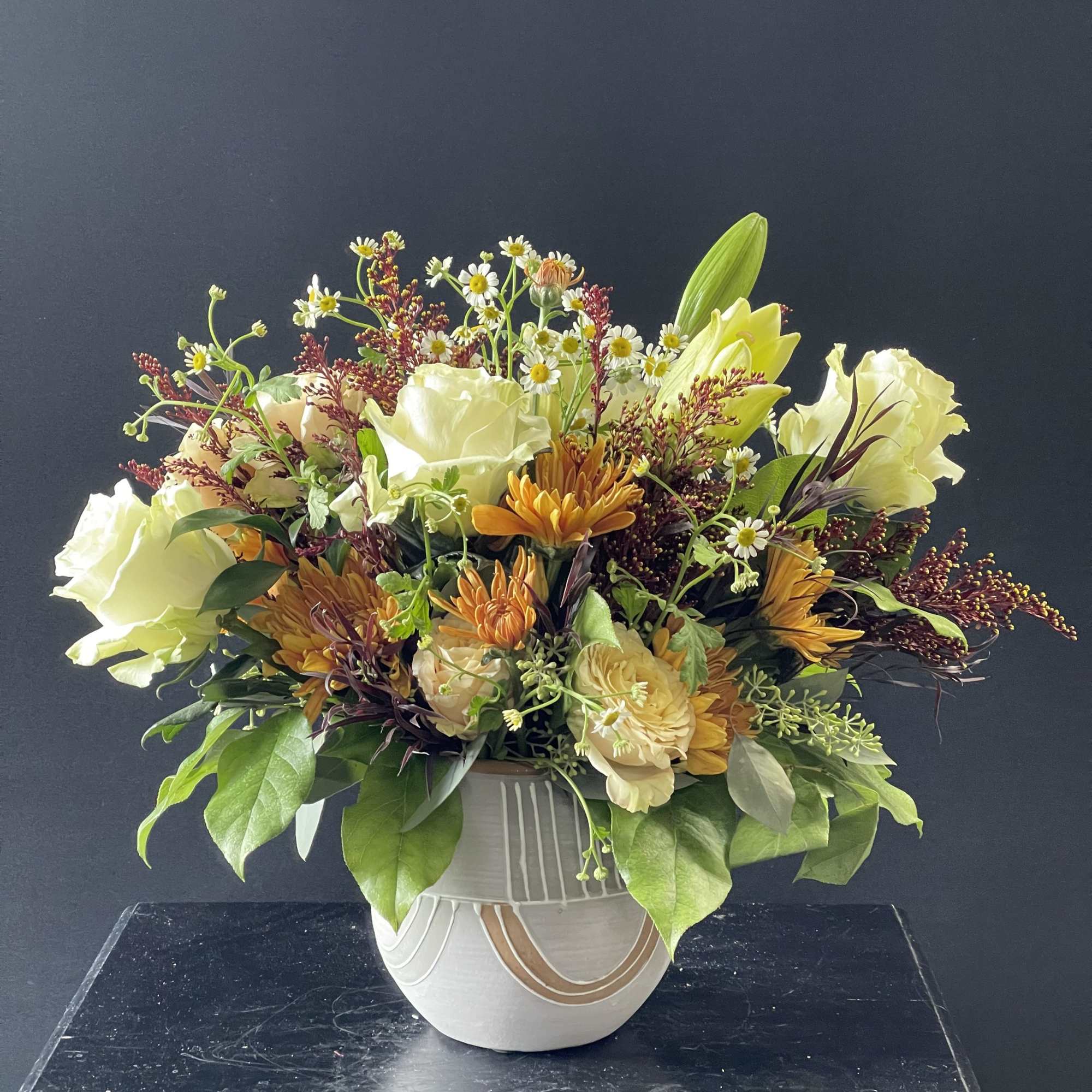 Mixed bouquet in a white ceramic vase with cream and orange flowers