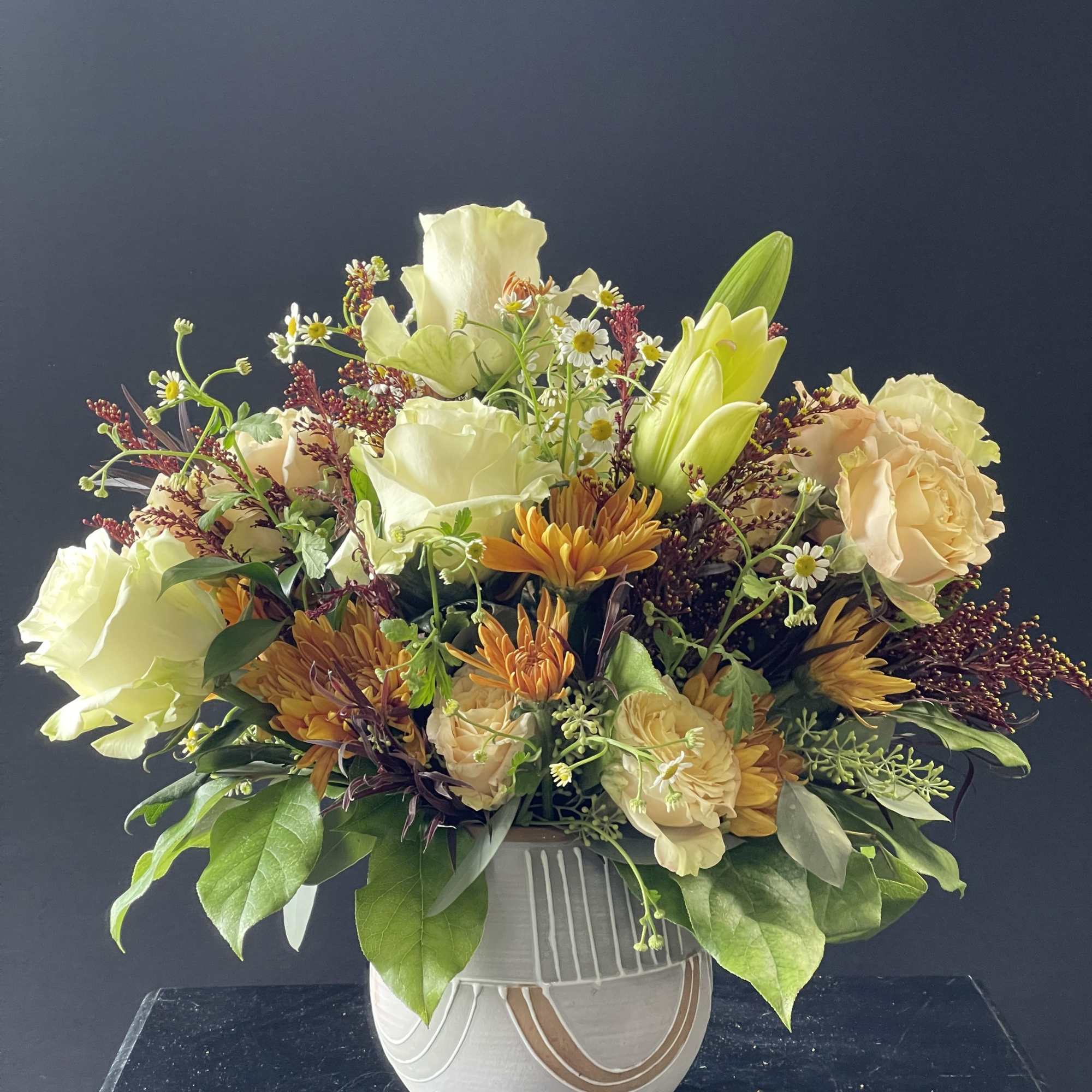 Cream and peach floral arrangement in a white ceramic vase