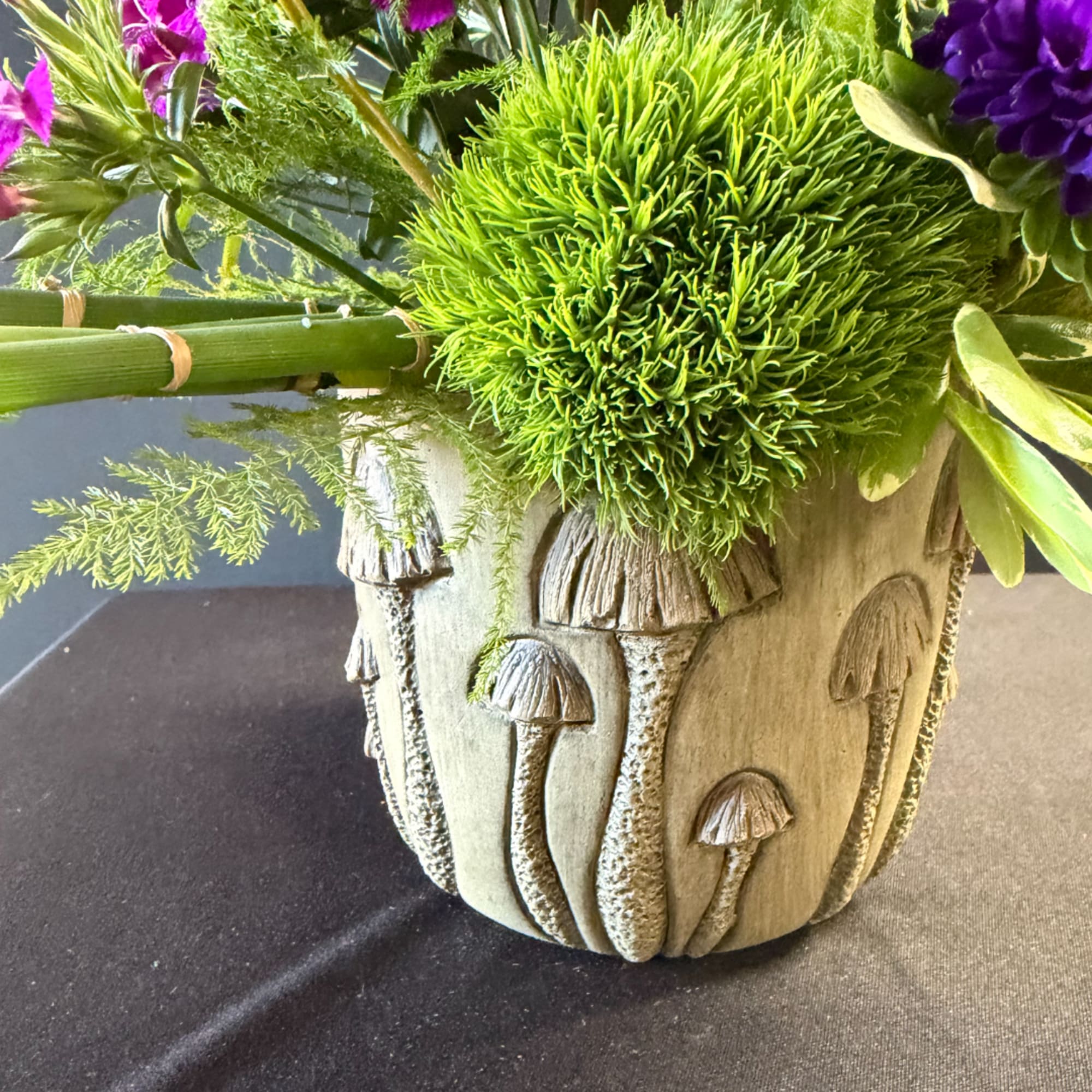 Green floral arrangement in a mushroom-patterned ceramic pot