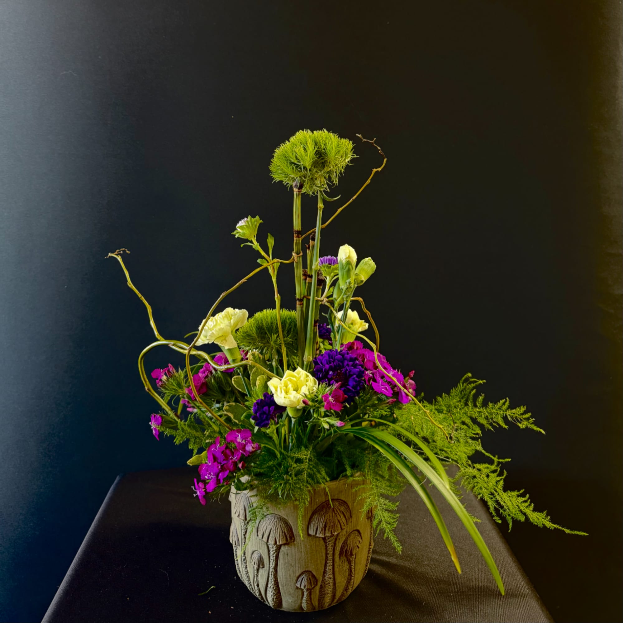 Mixed floral arrangement in a carved mushroom-patterned pot