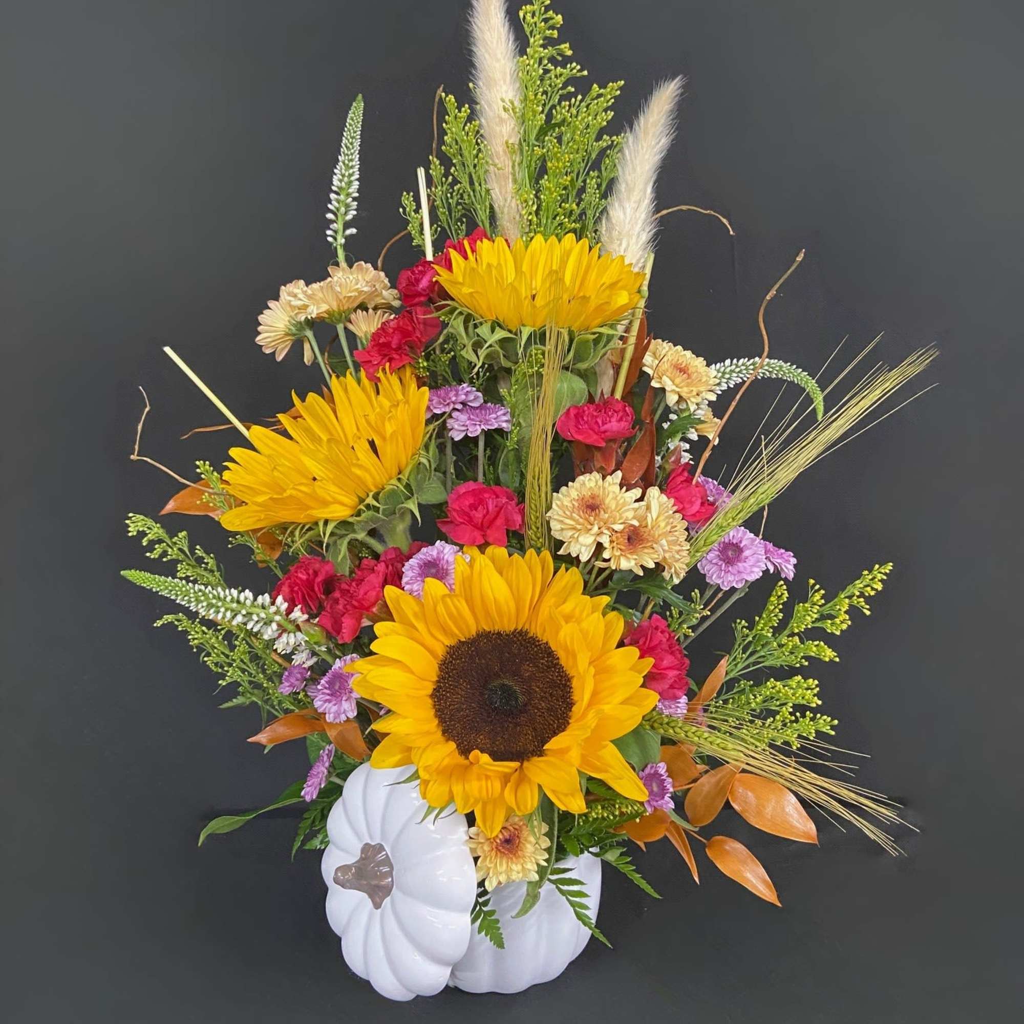 Sunflower arrangement in a white pumpkin container with mixed blooms and grasses
