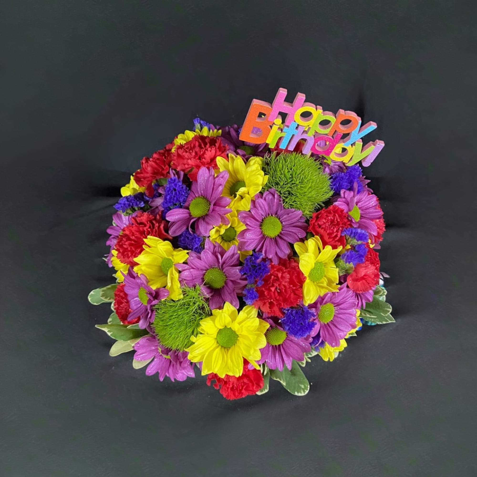 Colorful birthday bouquet with daisies and carnations on a dark background