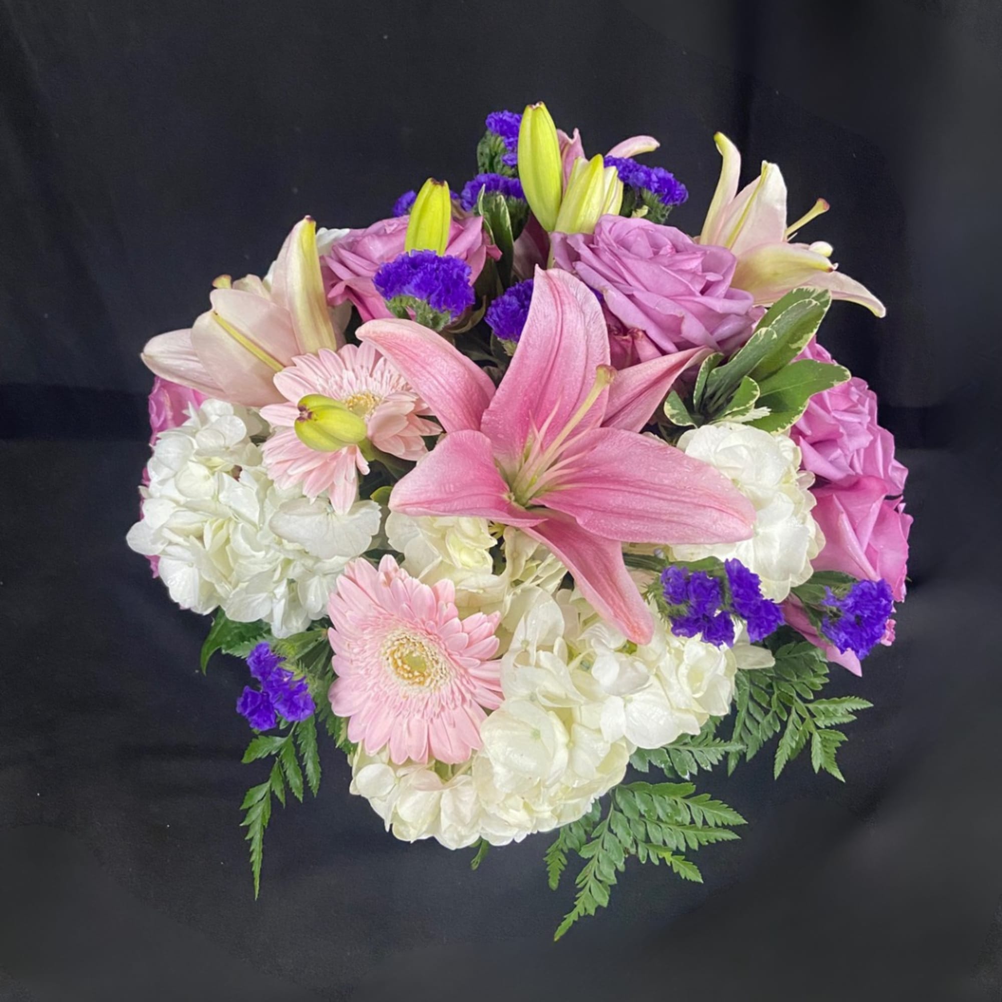 Pink lilies, roses, hydrangeas, and gerbera daisies in a bouquet