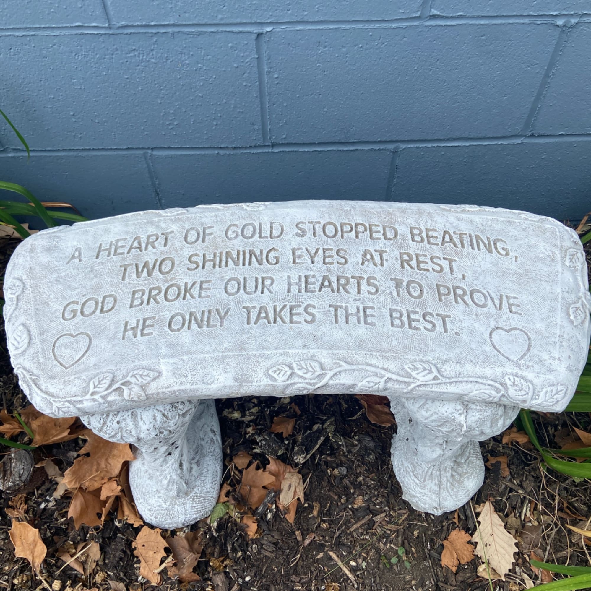 White memorial bench with engraved text and heart motifs outdoors