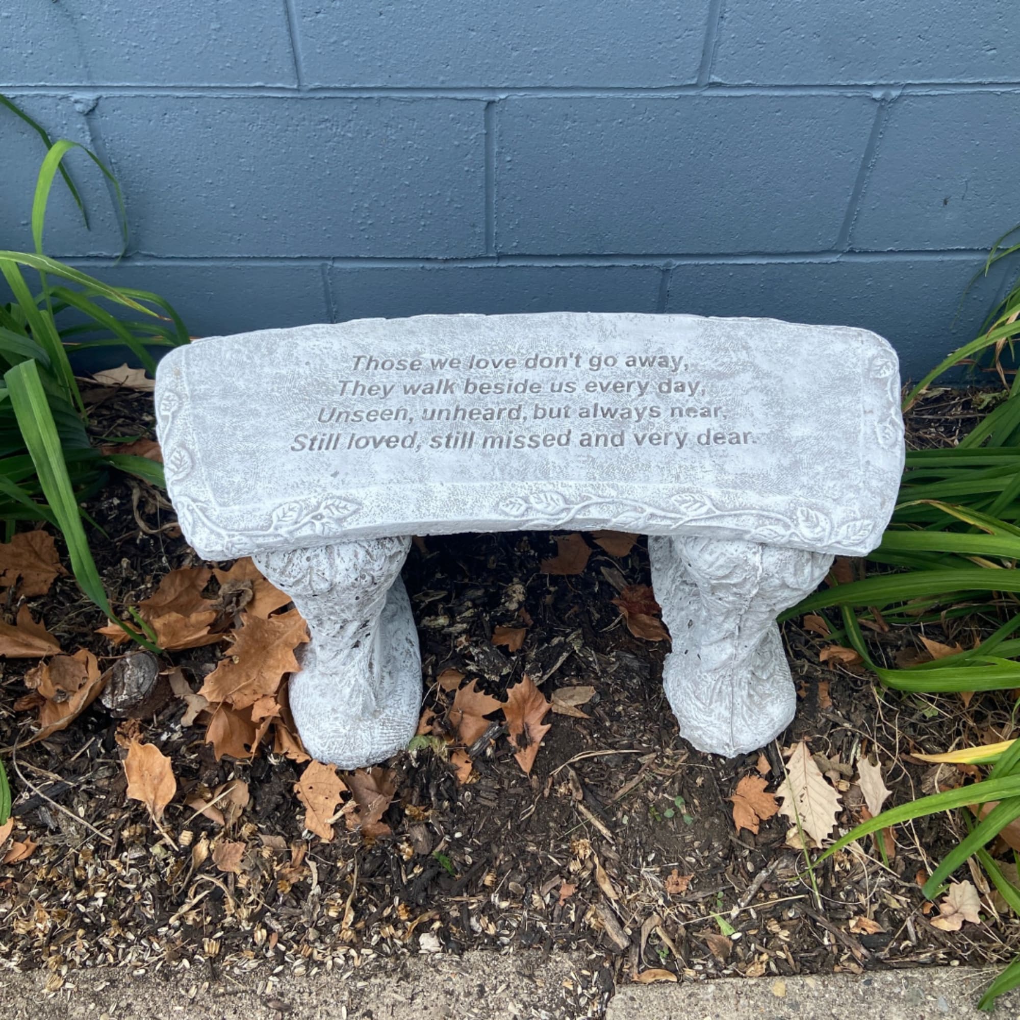 Stone memorial bench with an engraved sympathy quote outdoors