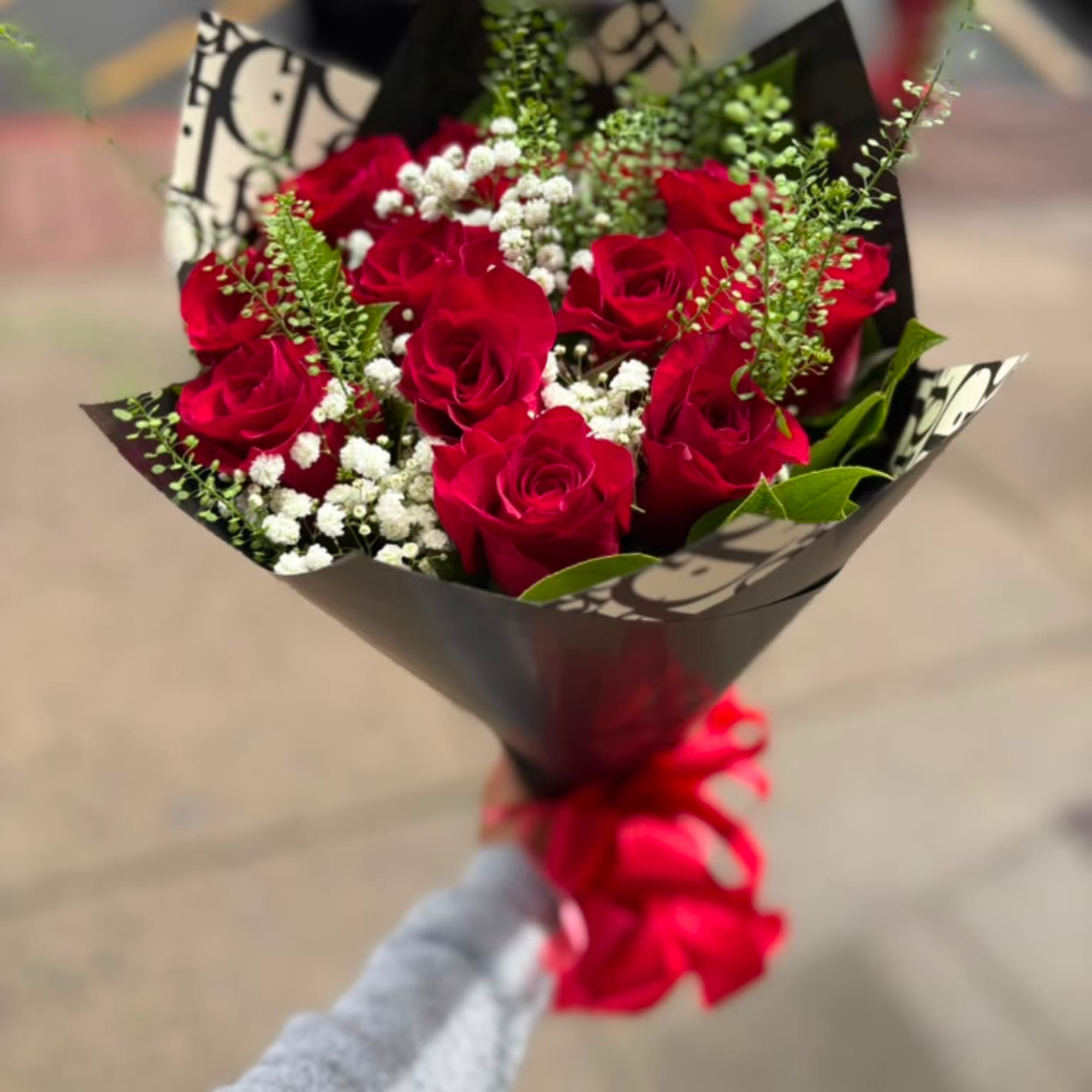 Bouquet of red roses with white filler flowers in black wrap