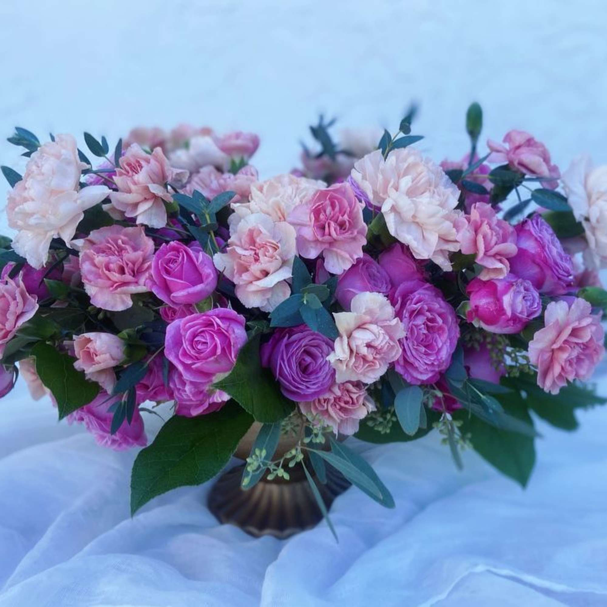 Pink and purple roses with carnations in a low vase