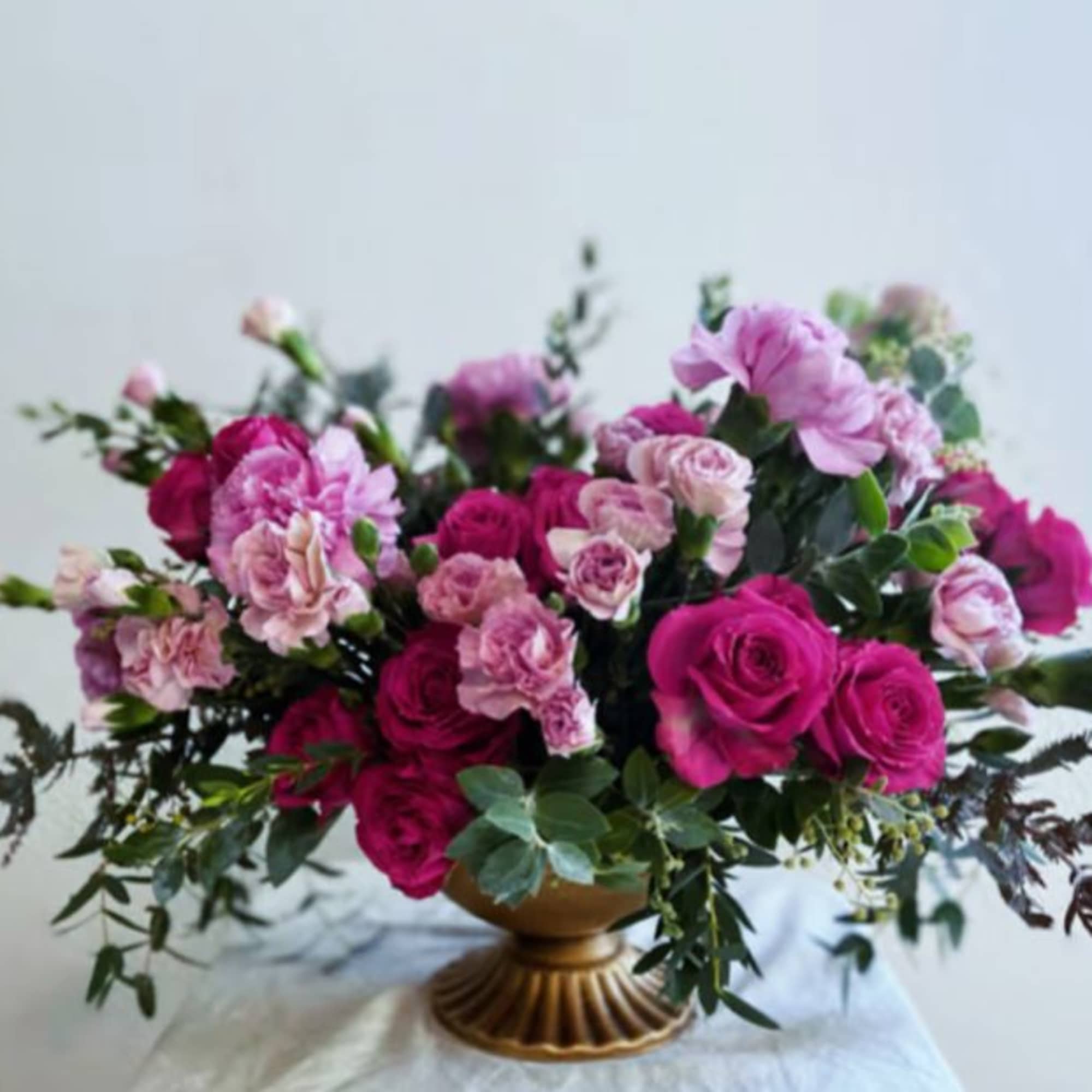 Pink roses and carnations in a gold pedestal vase