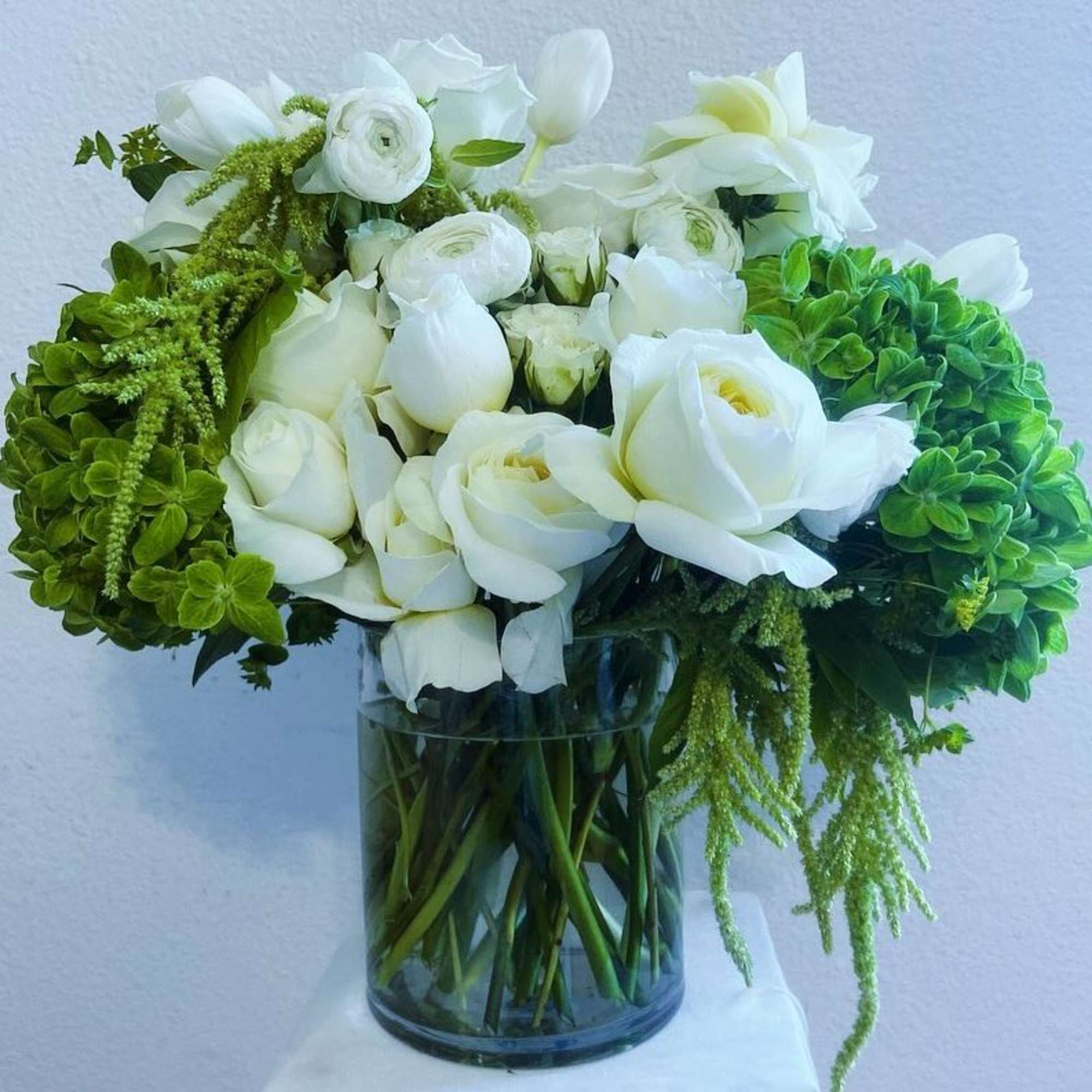 White flowers and green hydrangeas in a glass vase