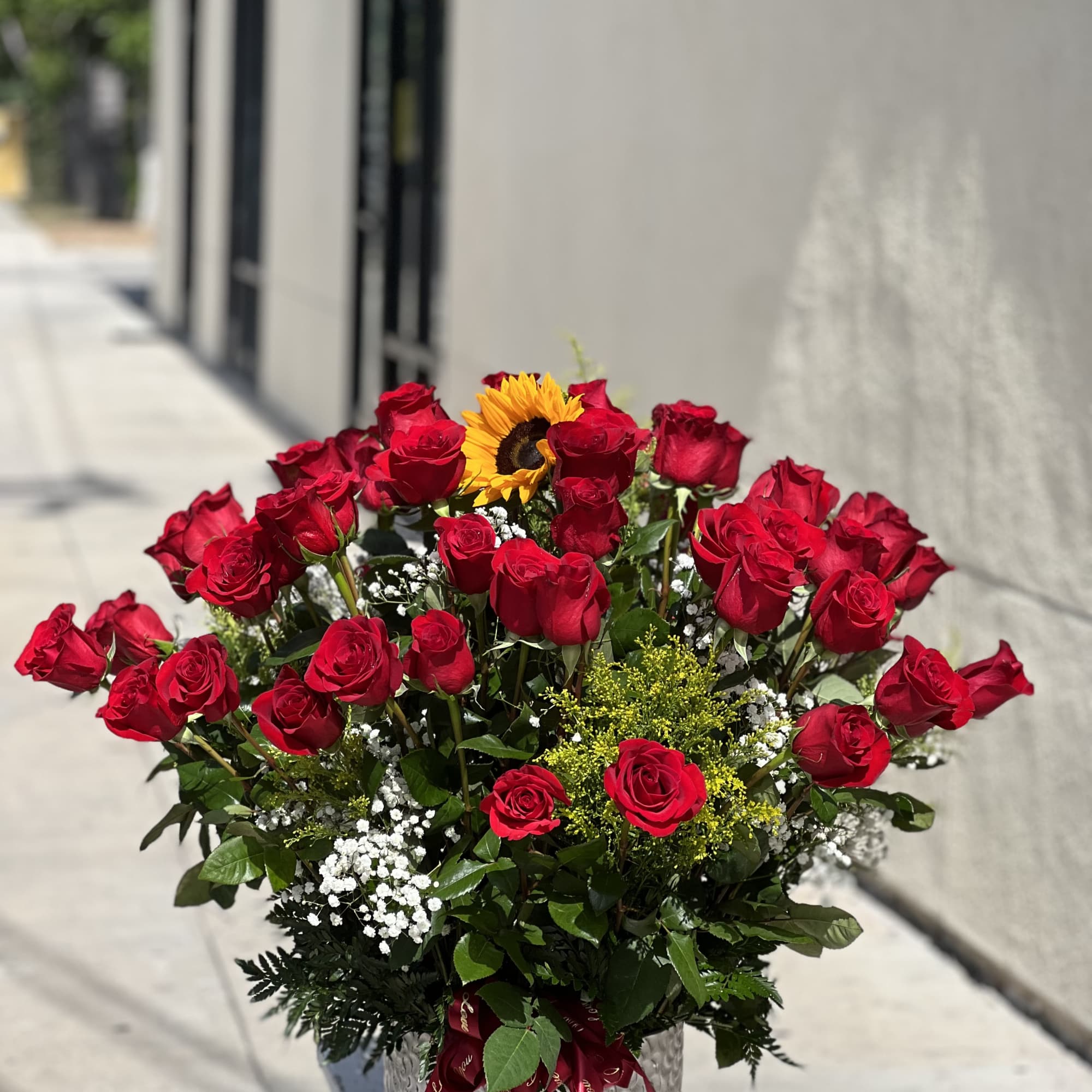 Bouquet of red roses with a sunflower in a silver vase