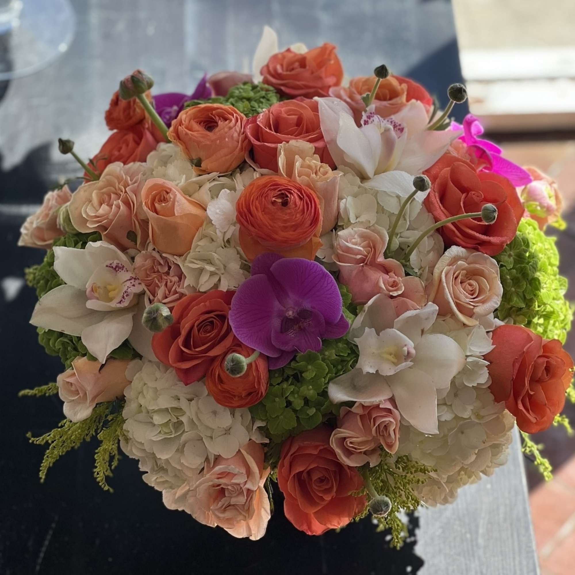 Round bouquet of coral and blush roses with white orchids and hydrangeas, photo 2 of 3