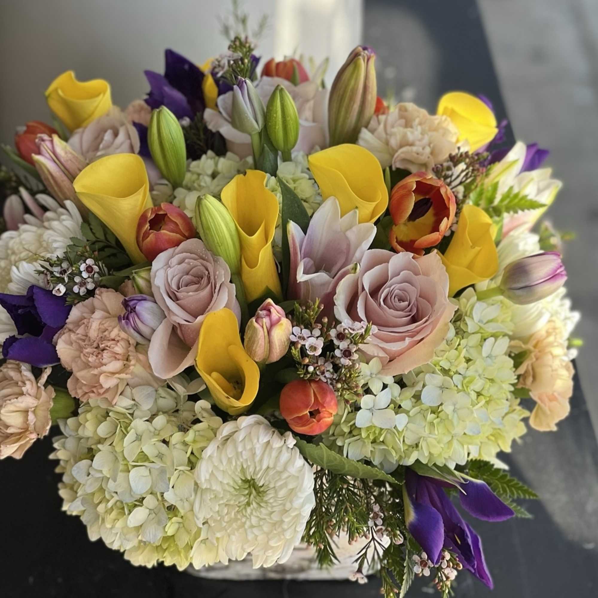 Mixed bouquet with yellow calla lilies, pale roses, and purple tulips