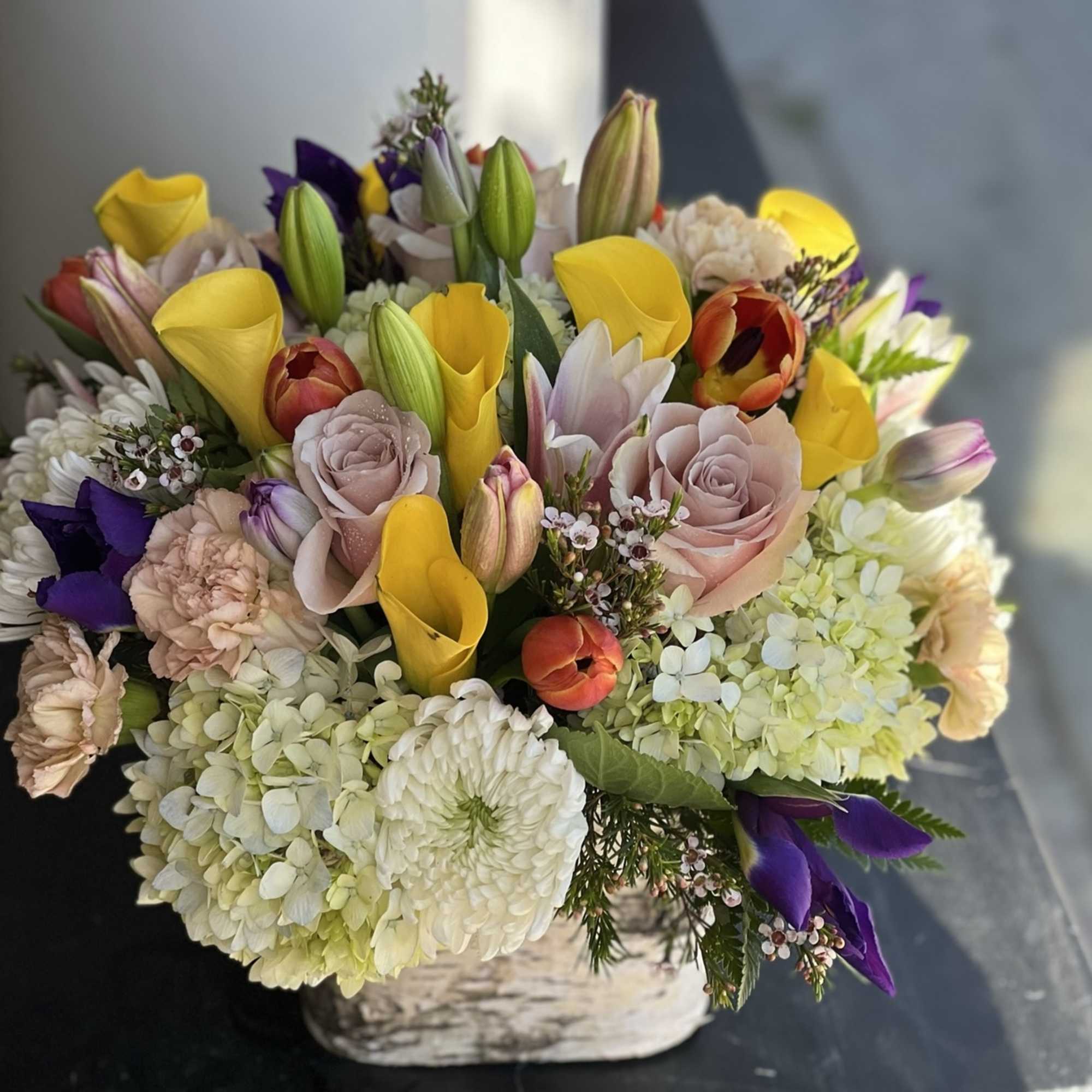 Mixed bouquet with yellow calla lilies, roses, and hydrangeas in a vase