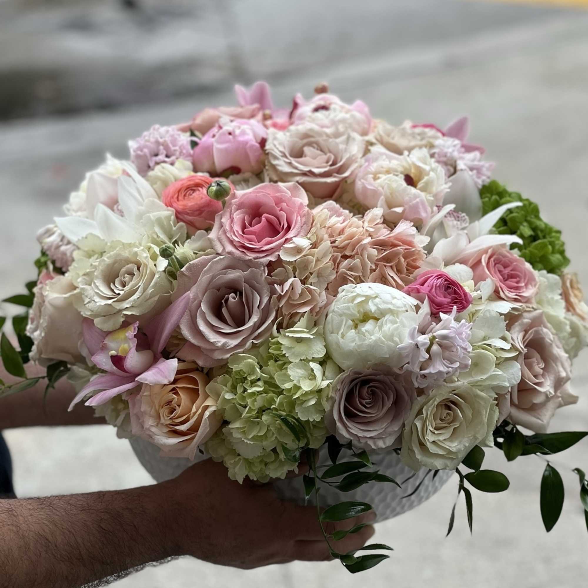 Round bouquet of pink and white roses with hydrangeas in a white container