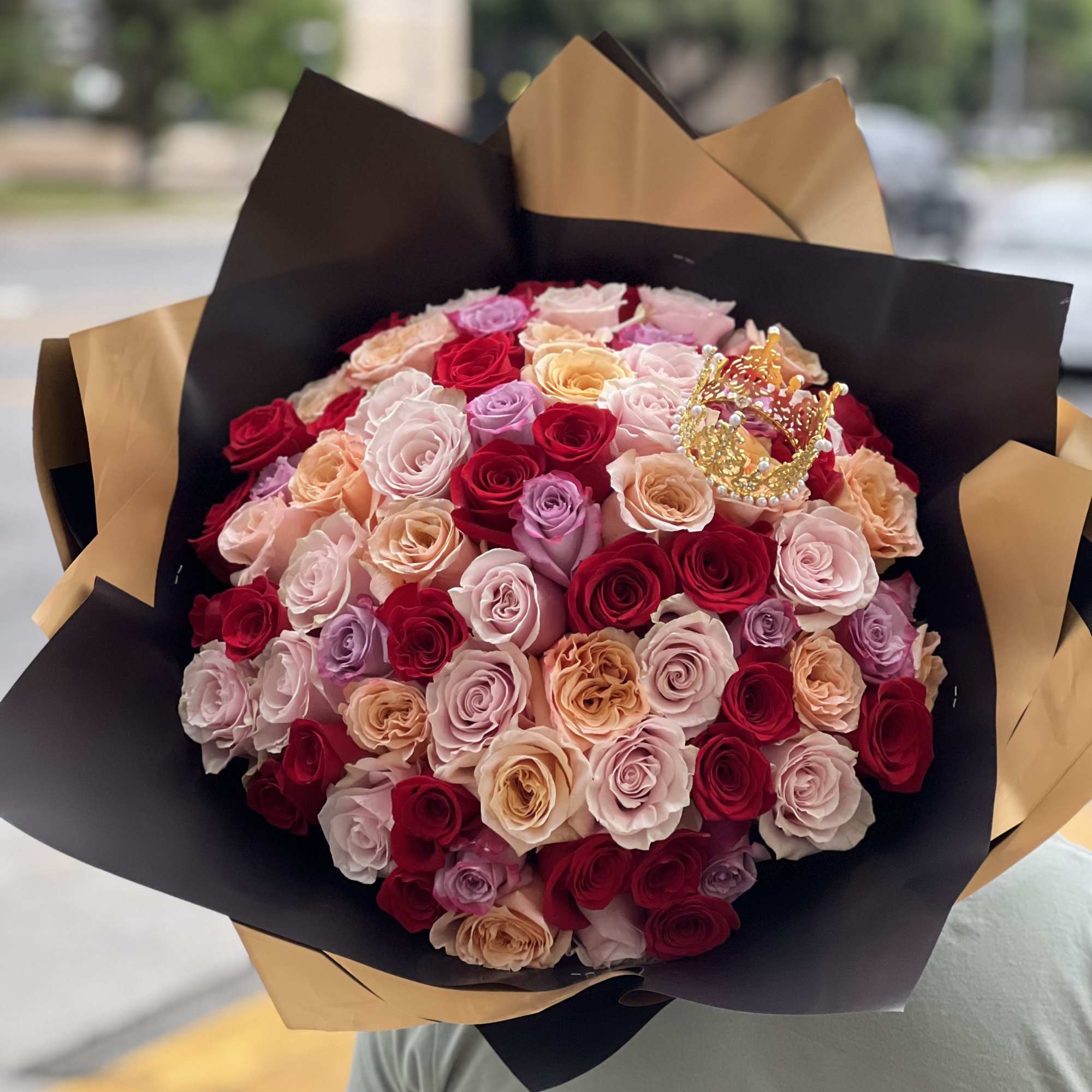 Large bouquet of multicolored roses wrapped in black and gold paper