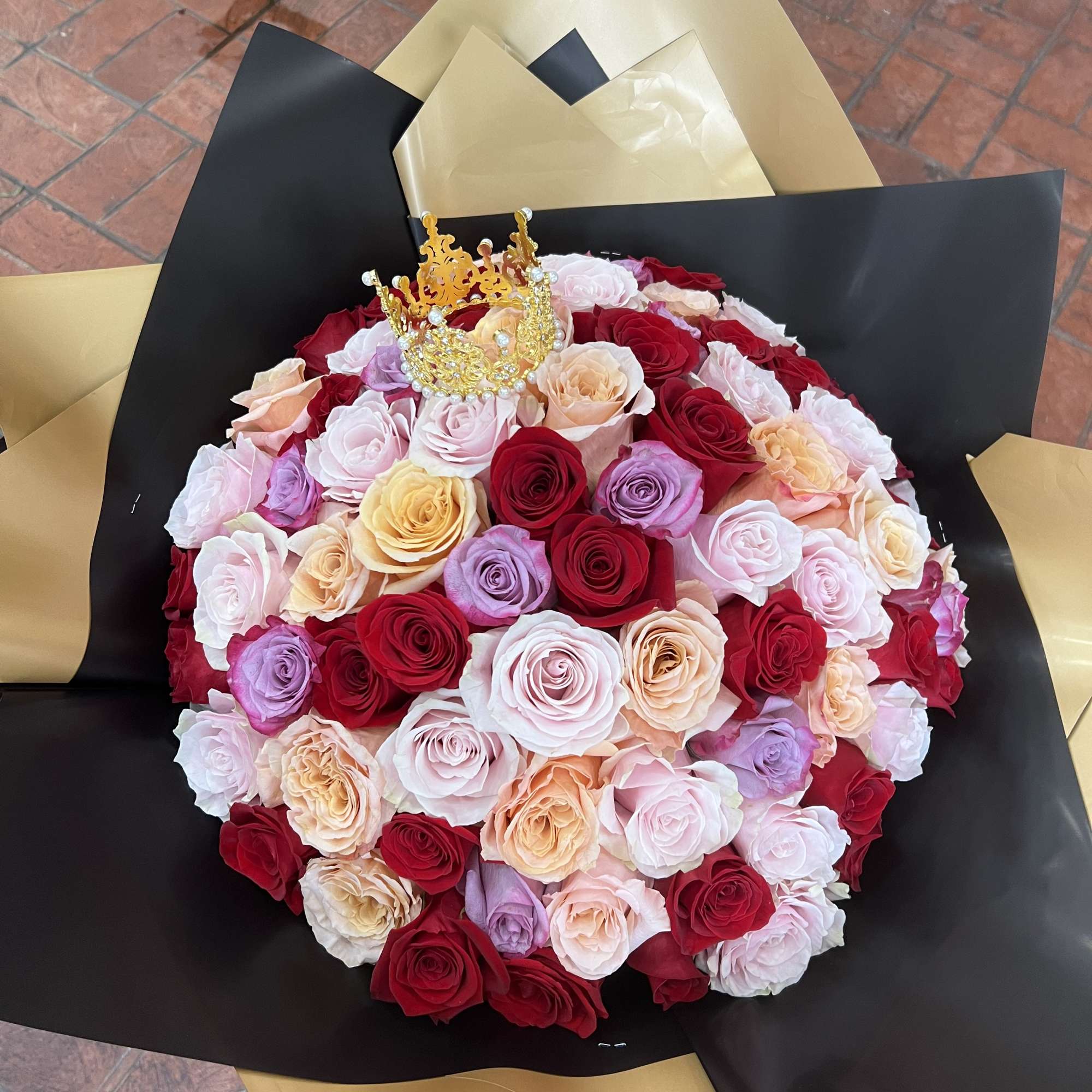 Large bouquet of multicolored roses with a gold crown topper