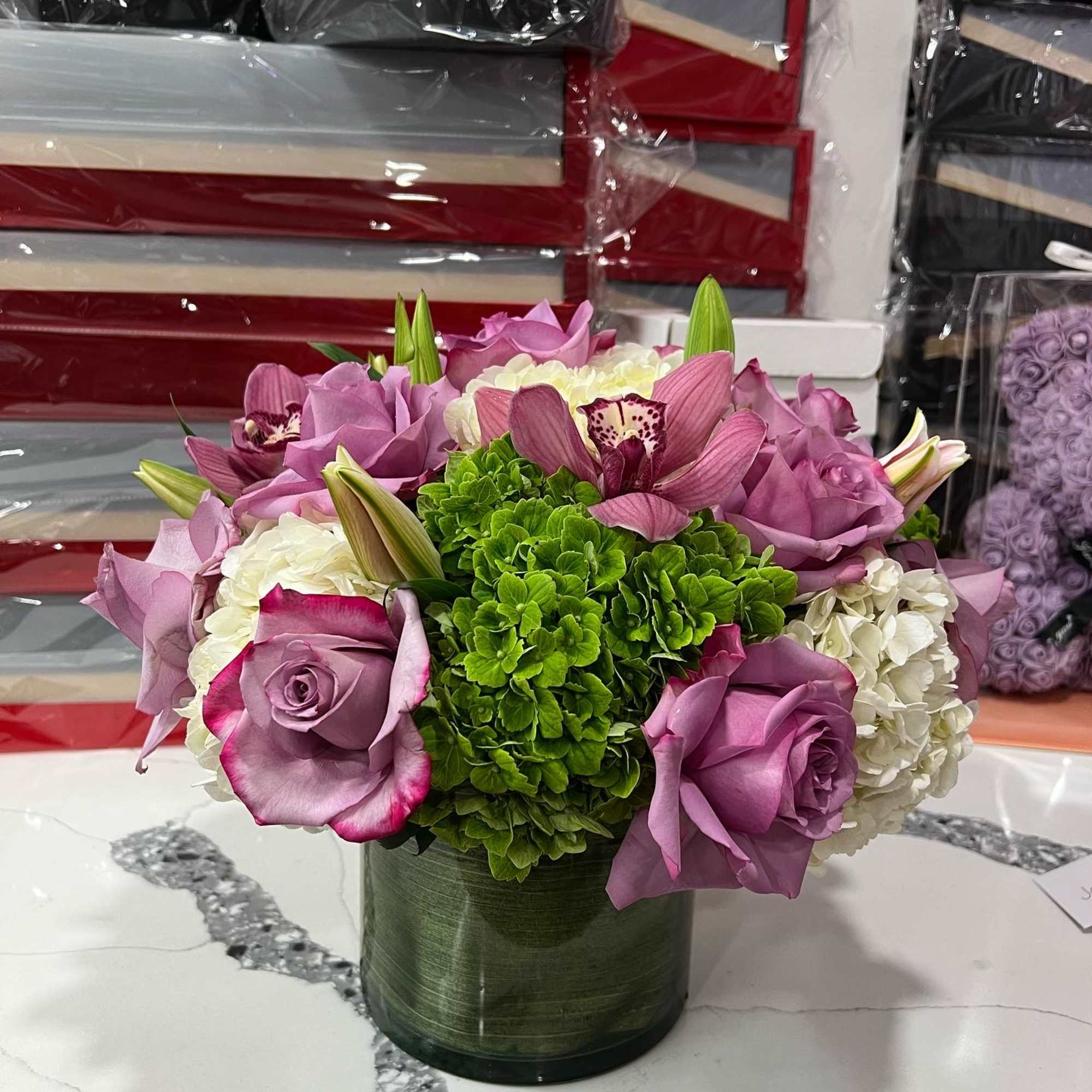 Lavender roses and white hydrangeas in a green glass vase