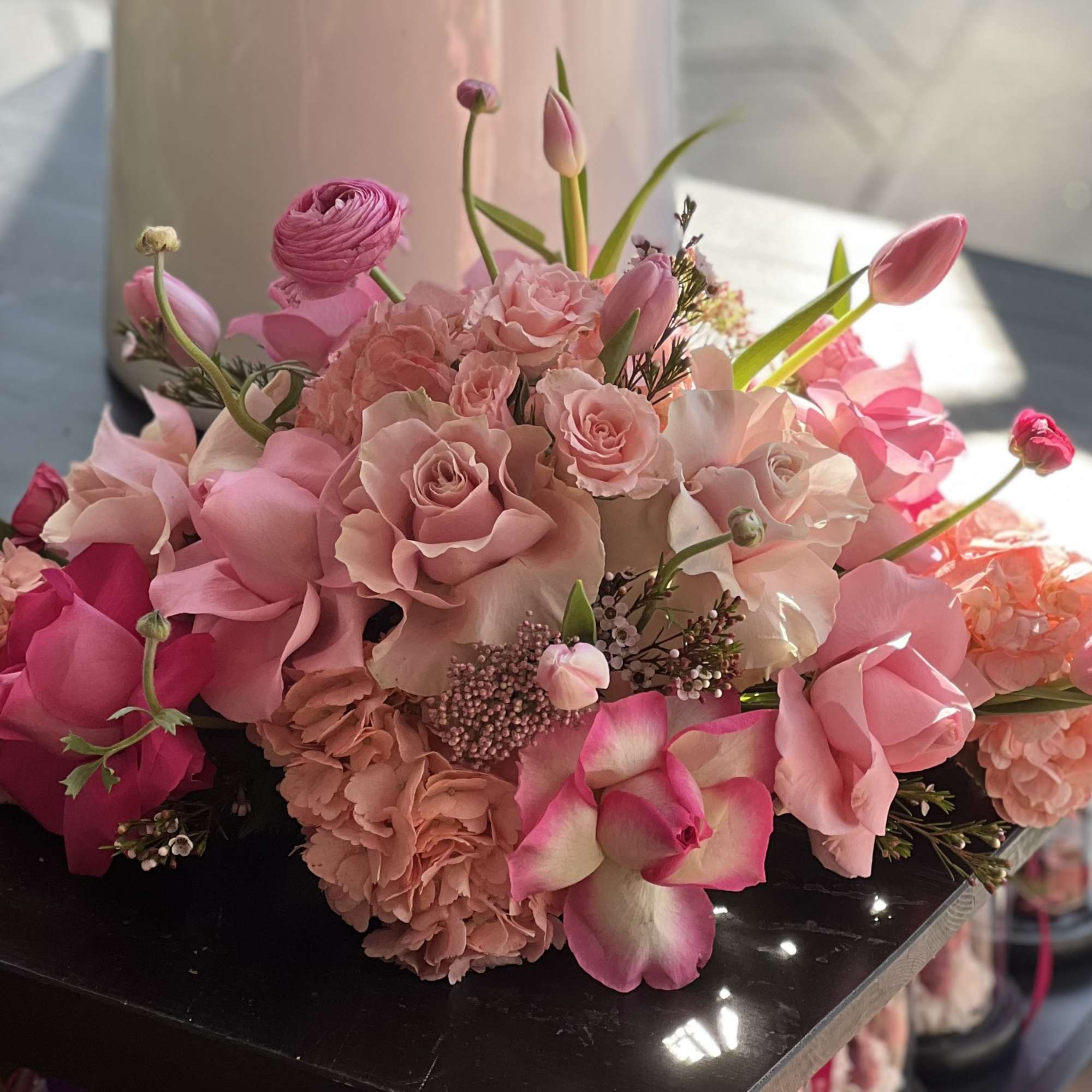 Pink bouquet with roses, tulips, and orchids arranged low and full