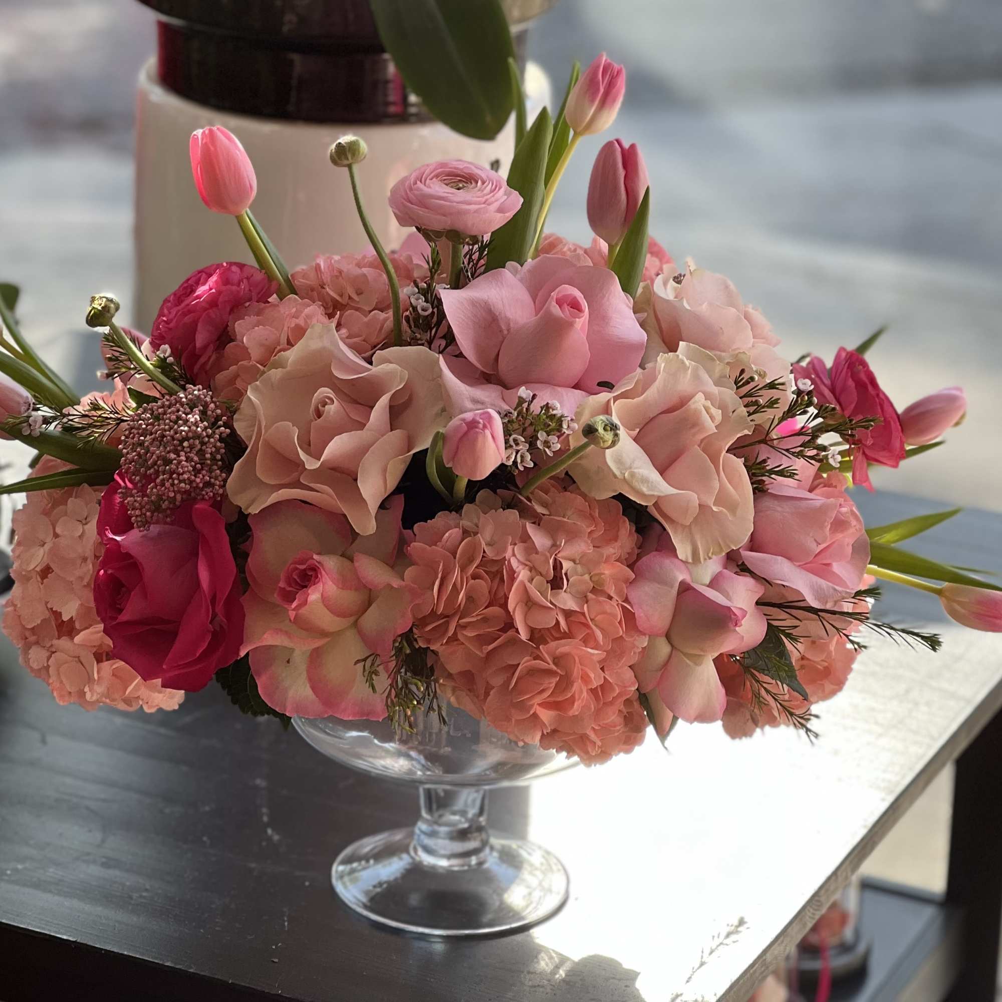 Pink floral arrangement in a clear pedestal vase