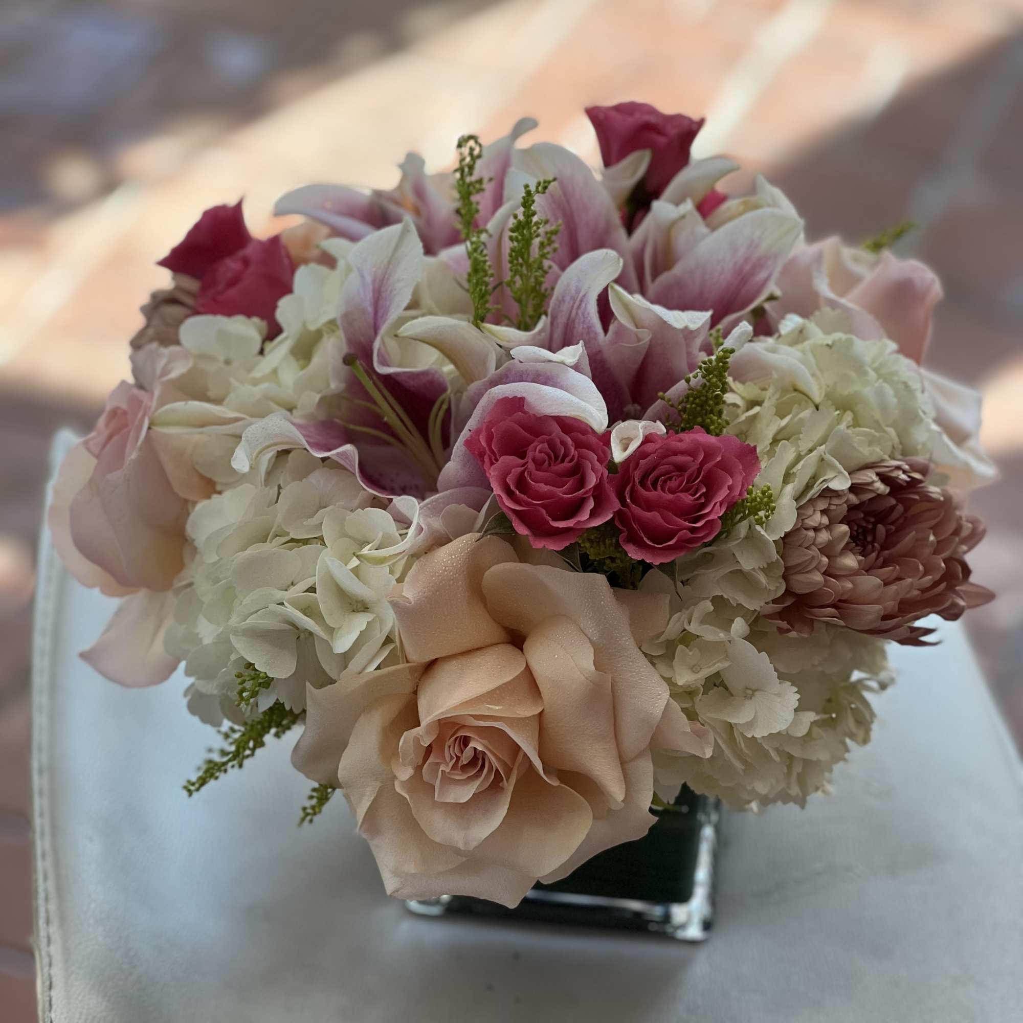 Pink and white bouquet with roses, lilies, and hydrangeas in a square vase